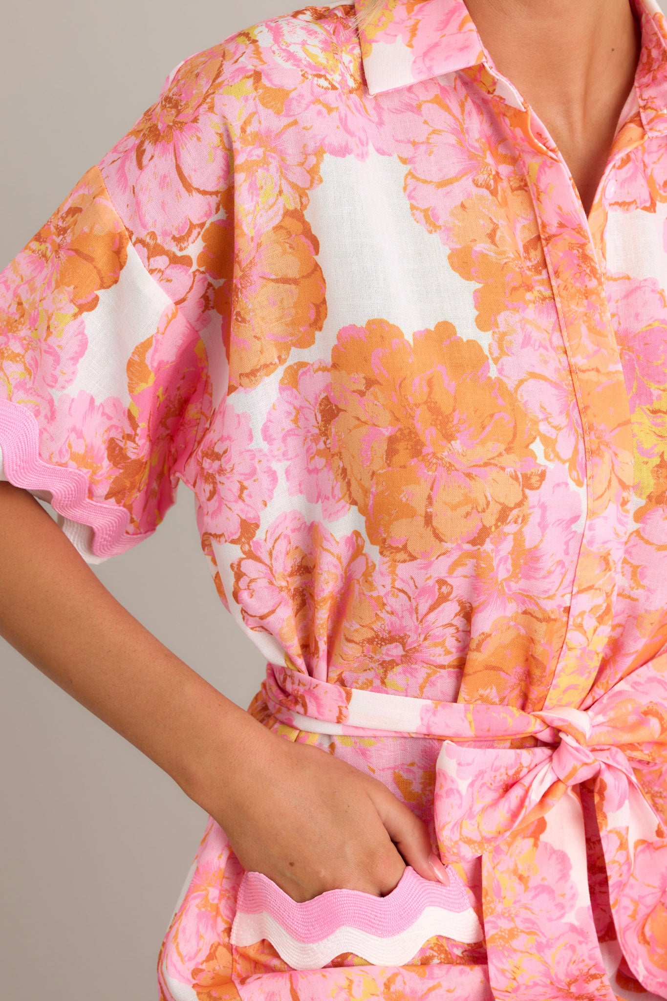 Close-up of the light pink floral mini dress showing the collared neckline, functional button front, and ricrac trim throughout.