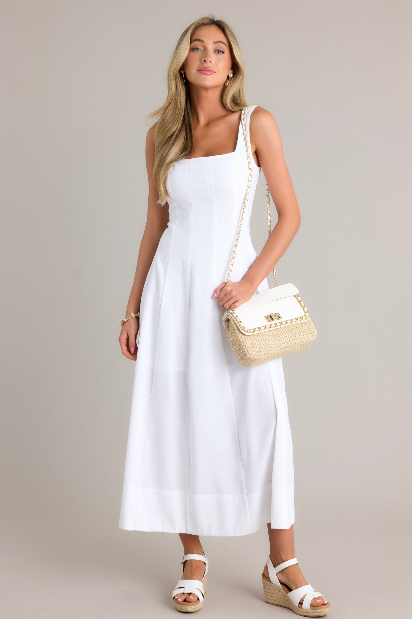 Action shot of a white maxi dress displaying the fit and movement, highlighting the square neckline, thick straps, flowing silhouette, and thick hemline.