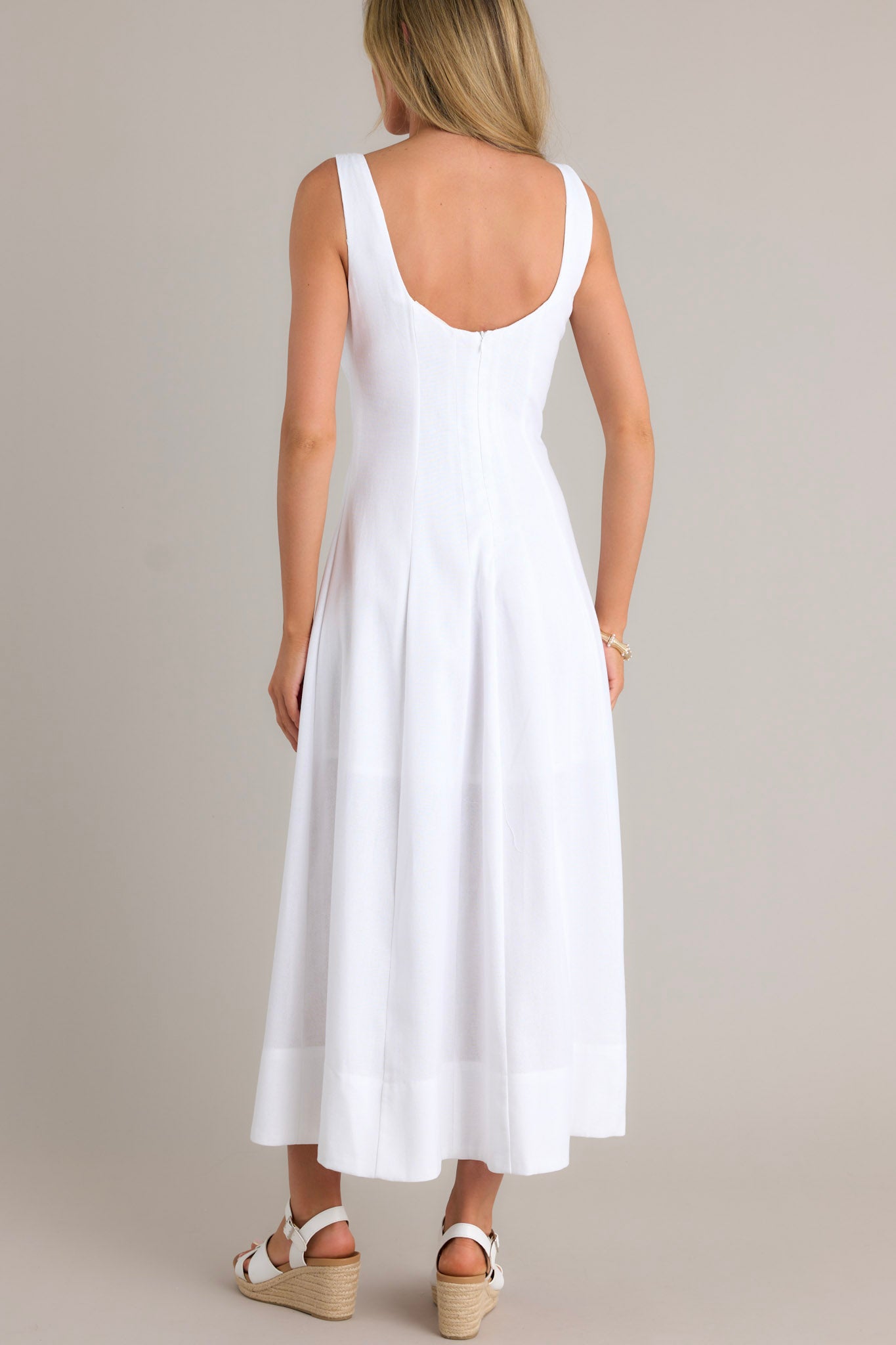 Back view of a white maxi dress highlighting the discrete back zipper, thick straps, and overall fit.
