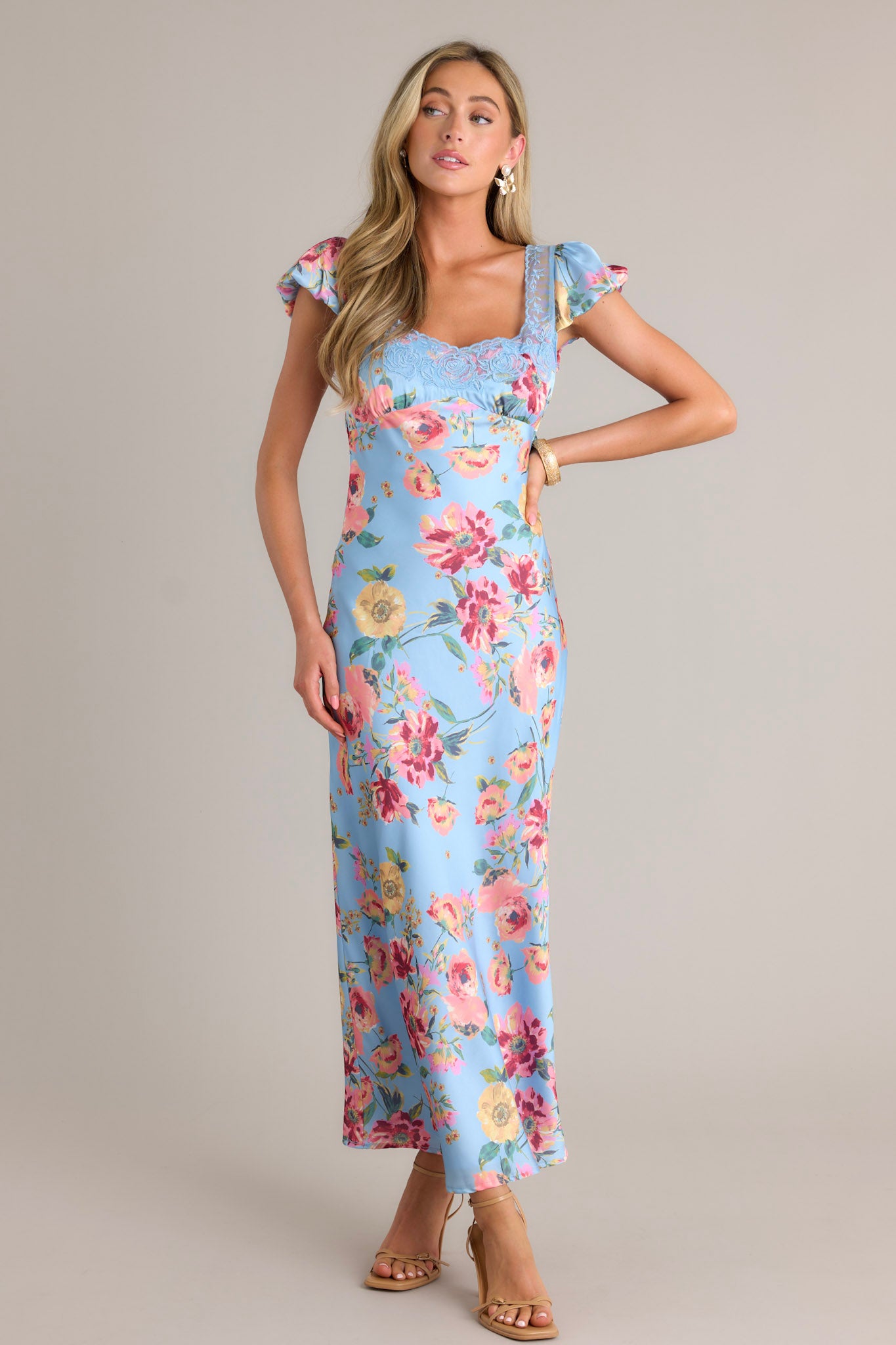 Front angled view of a sky blue maxi dress featuring a lace sweetheart neckline, a lace bust, functional buttons down the back, a lower back cutout, and short puffed sleeves