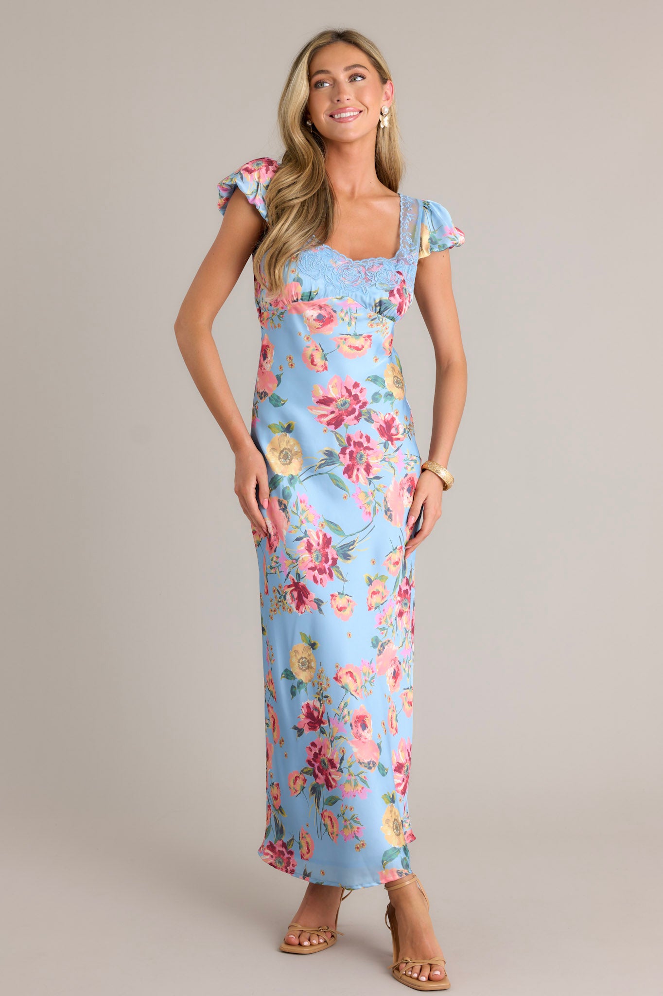 Full length view of a sky blue maxi dress with a lace sweetheart neckline, a lace bust, functional buttons down the back, a lower back cutout, and short puffed sleeves