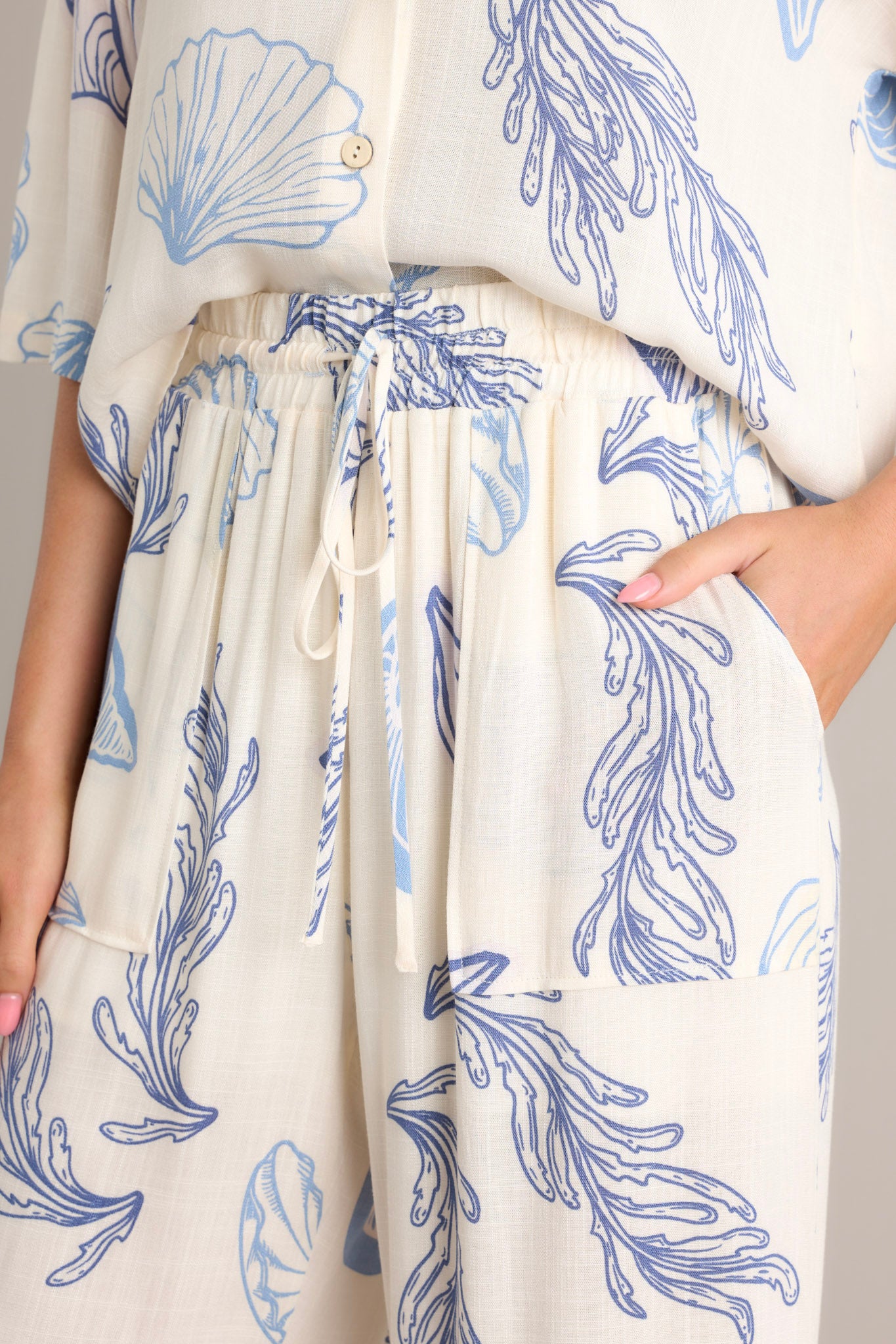 Close-up of the pants showing the elastic waistband, drawstring tie, and beachy seashell print.