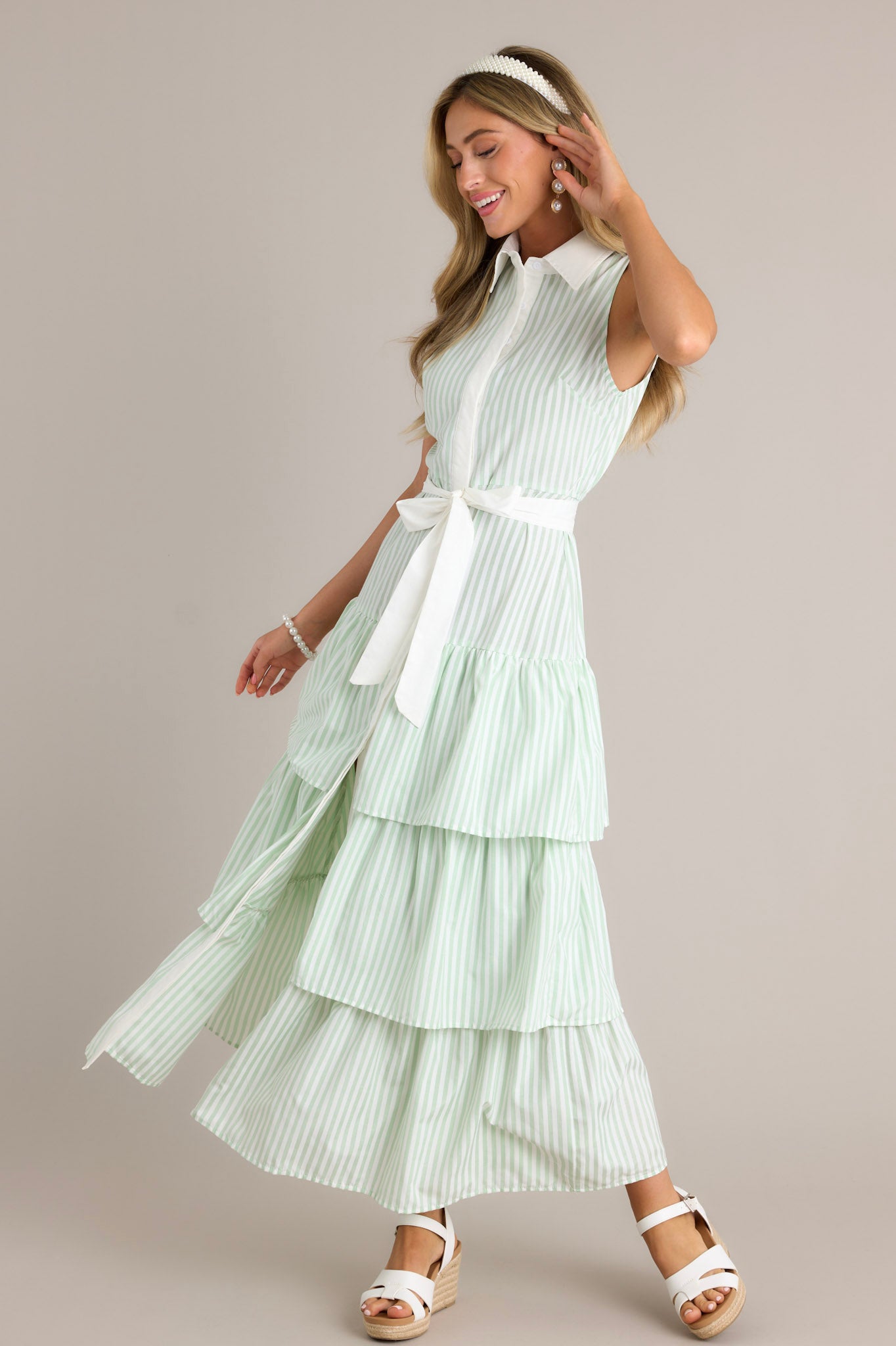 This mint green stripe maxi dress features a collared neckline, a button front, an elastic waist insert, a self-tie waist belt, and multiple tiers.