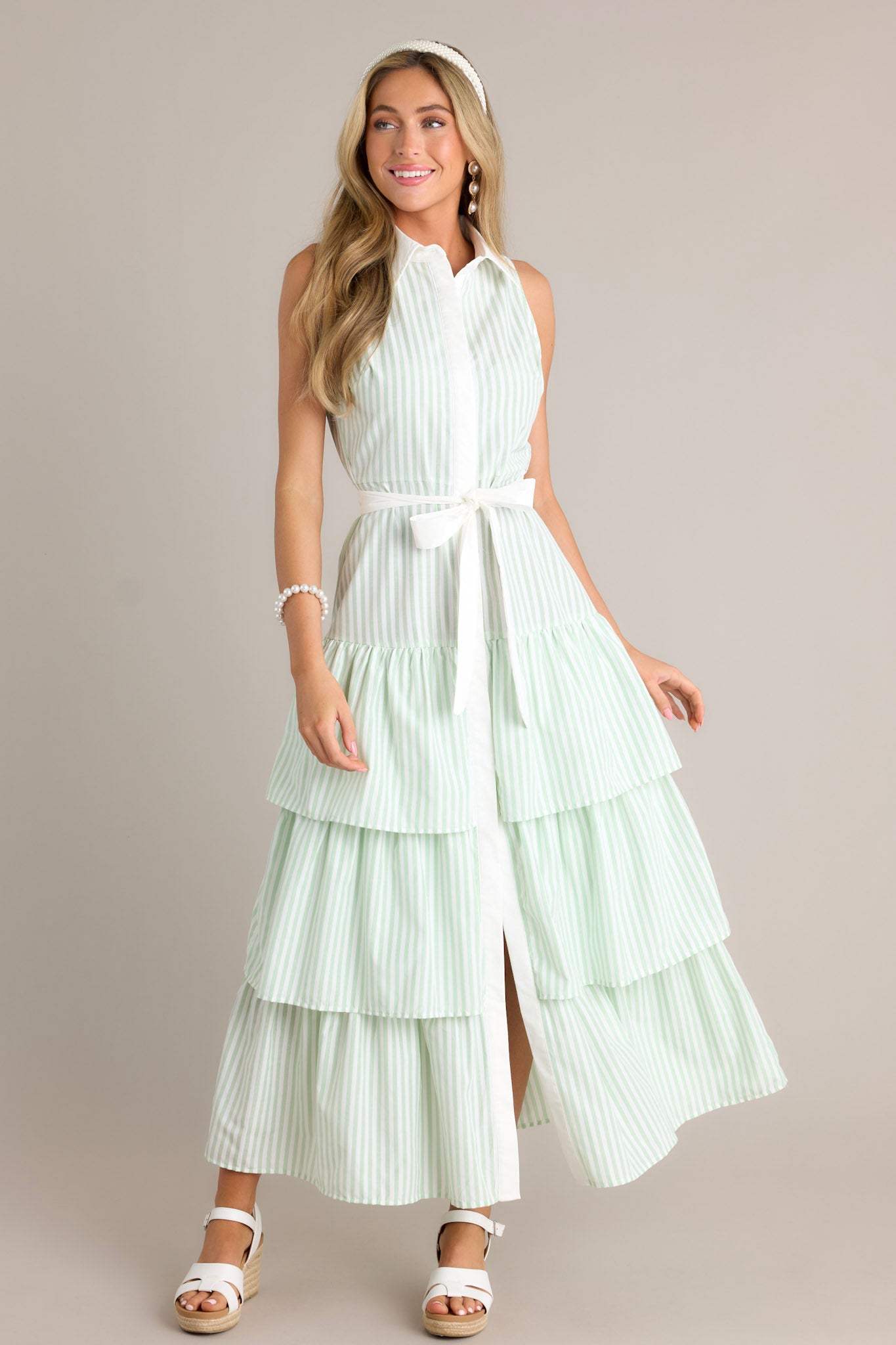 Action shot of a mint green stripe maxi dress displaying the fit and movement, highlighting the collared neckline, button front, elastic waist insert, self-tie waist belt, and multiple tiers.