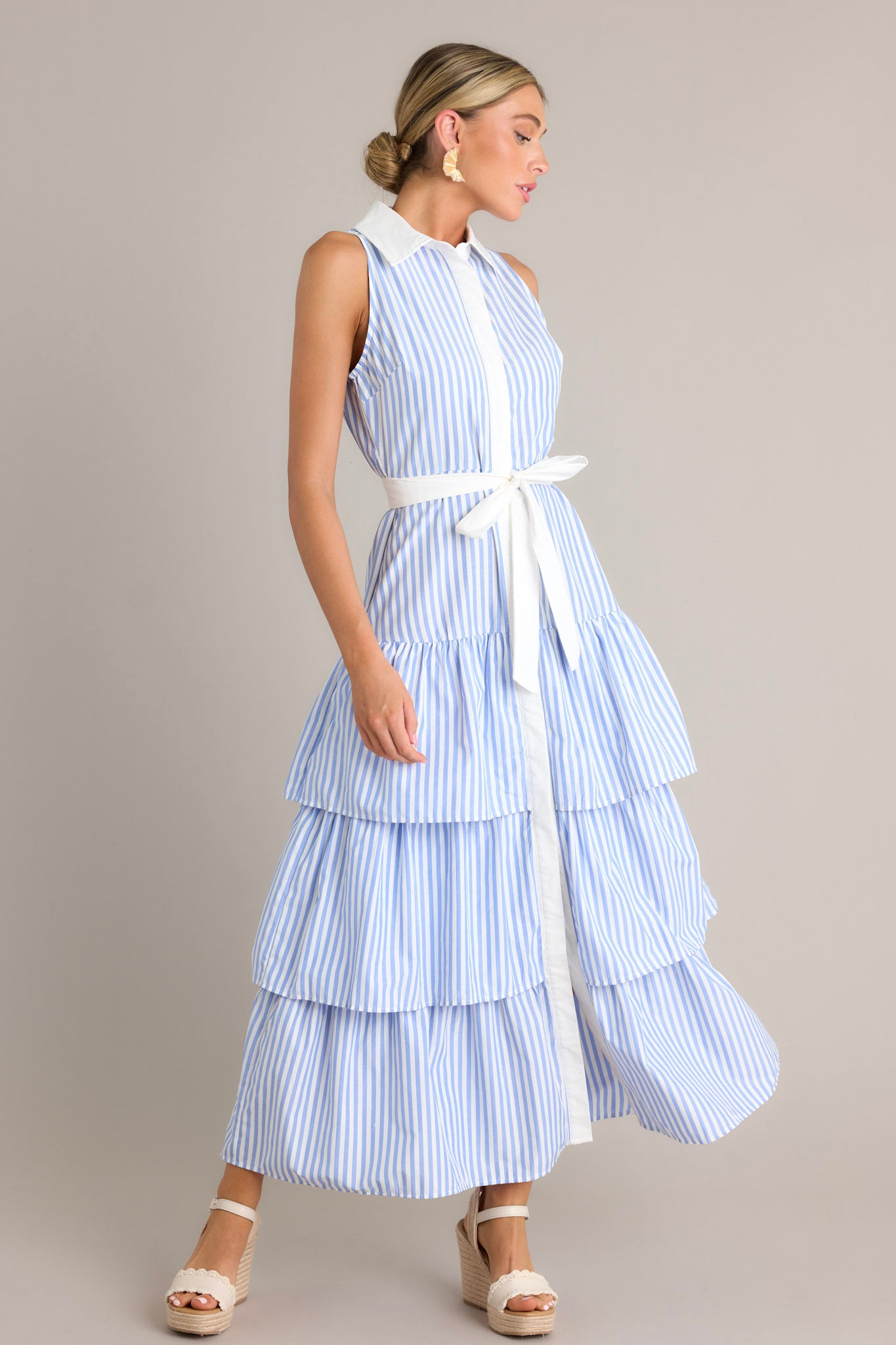 Side view of a blue stripe maxi dress showcasing the collared neckline, button front, elastic waist insert, self-tie waist belt, and multiple tiers.