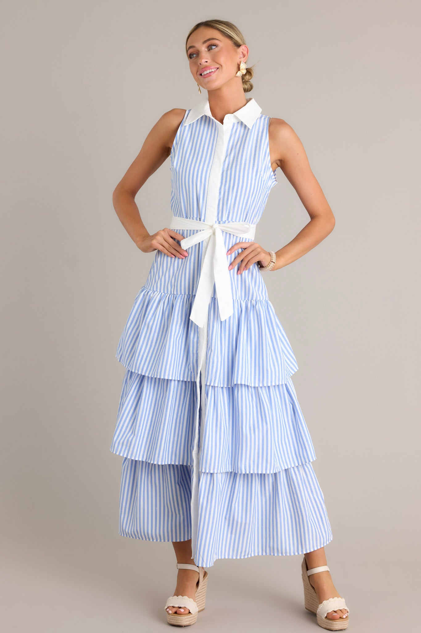 Full length view of a blue stripe maxi dress with a collared neckline, a button front, an elastic waist insert, a self-tie waist belt, and multiple tiers