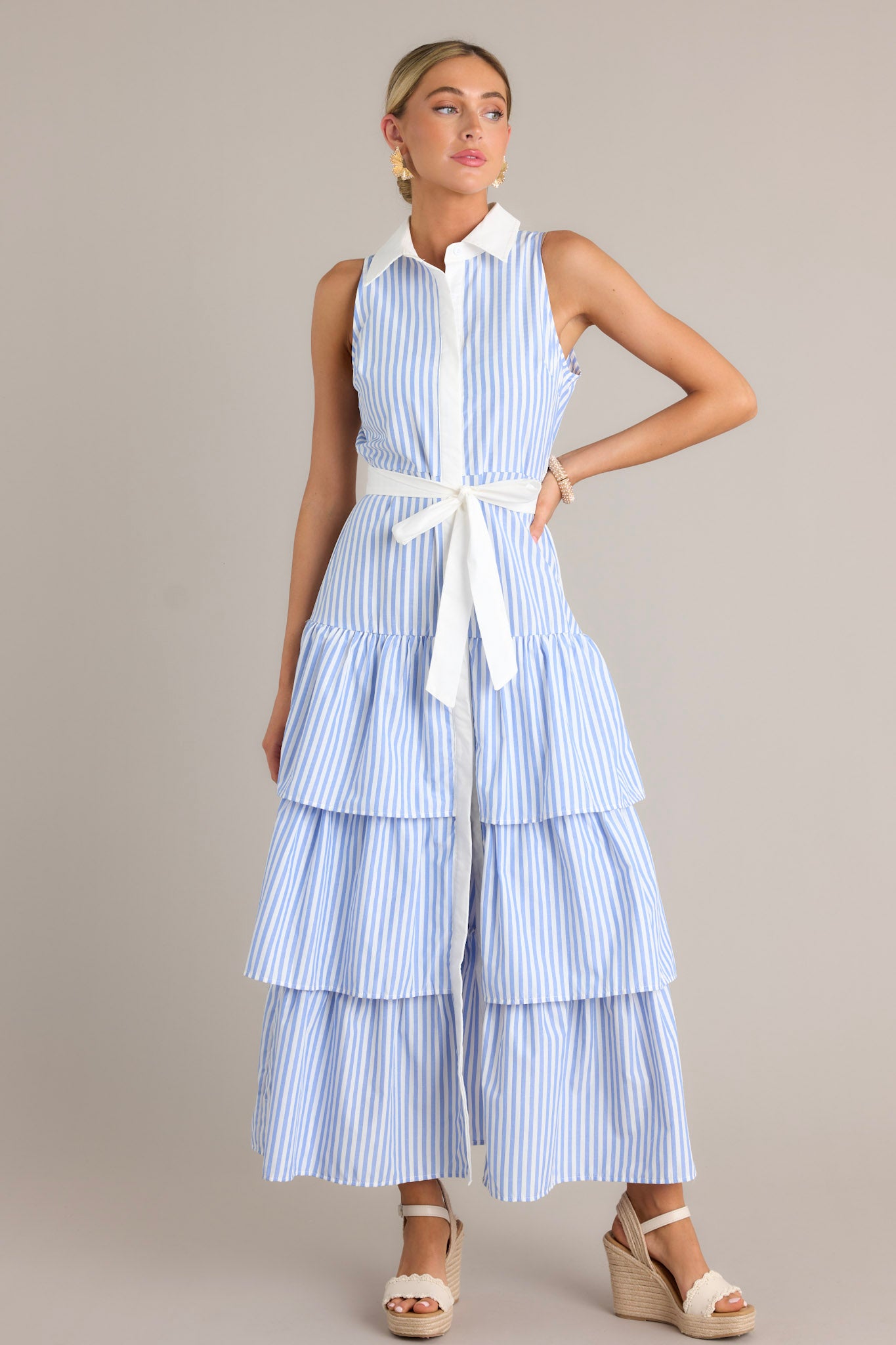 Front view of a blue stripe maxi dress featuring a collared neckline, a button front, an elastic waist insert, a self-tie waist belt, and multiple tiers.