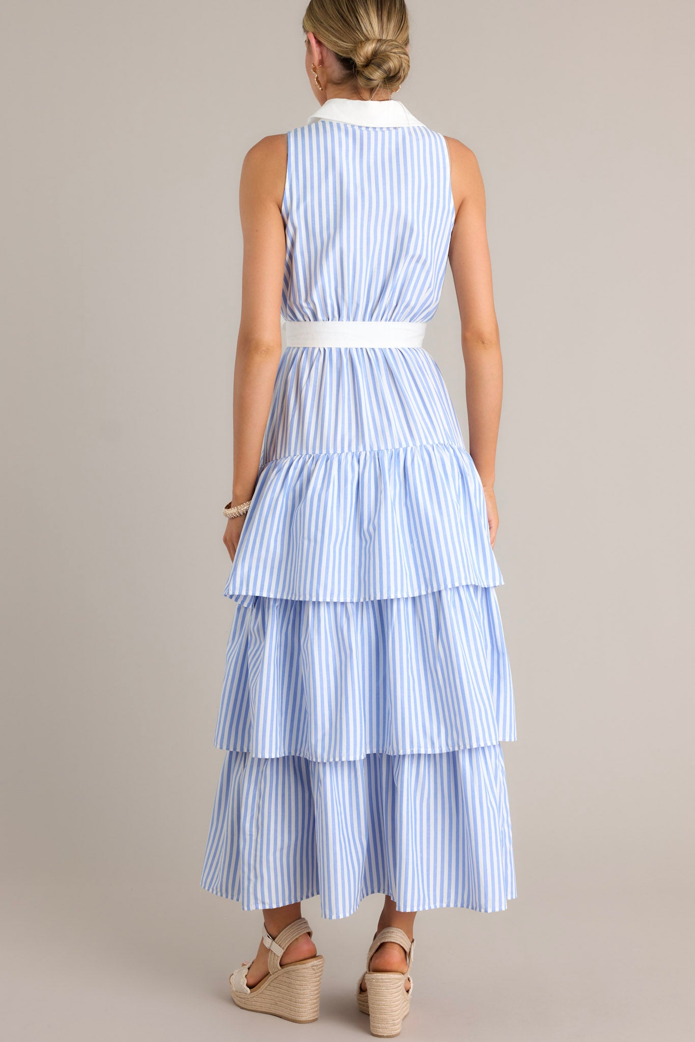 Back view of a blue stripe maxi dress highlighting the collared neckline, elastic waist insert, and the multiple tiers.