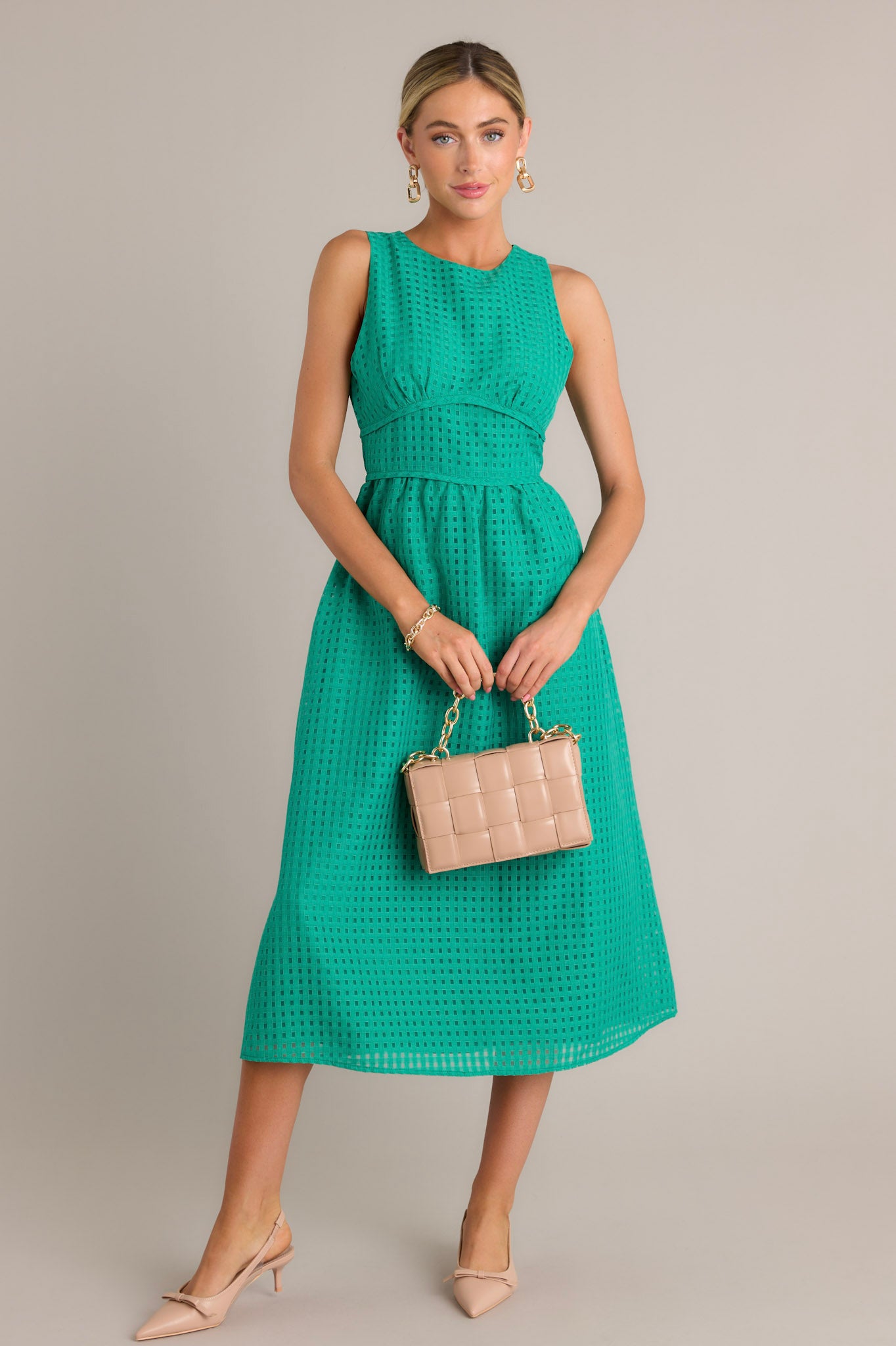 This green midi dress features a high neckline, a discrete back zipper, a thick waistband, a grid-like pattern, and a sleeveless design.