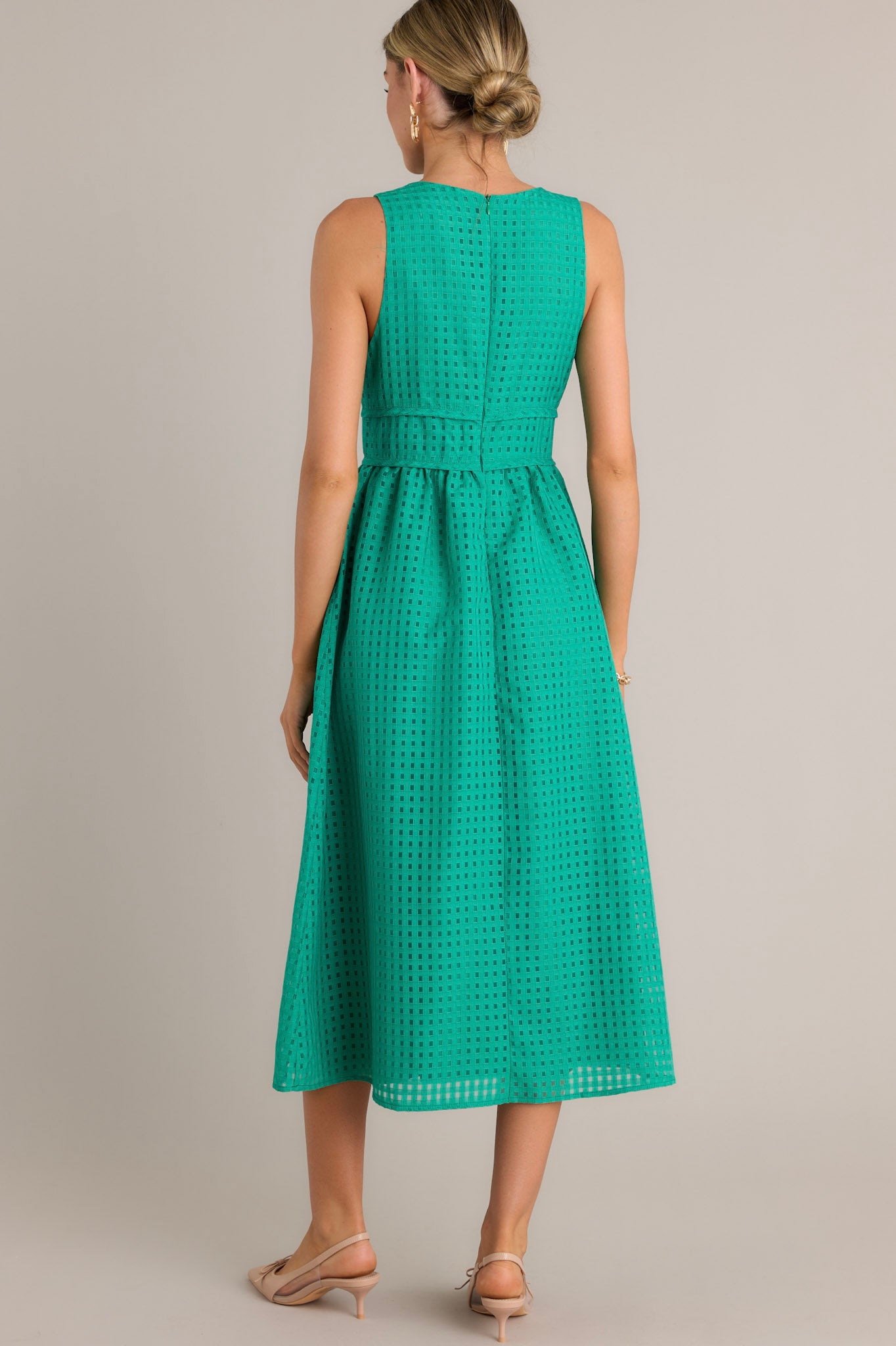 Back view of a green midi dress highlighting the discrete back zipper, thick waistband, and overall fit.