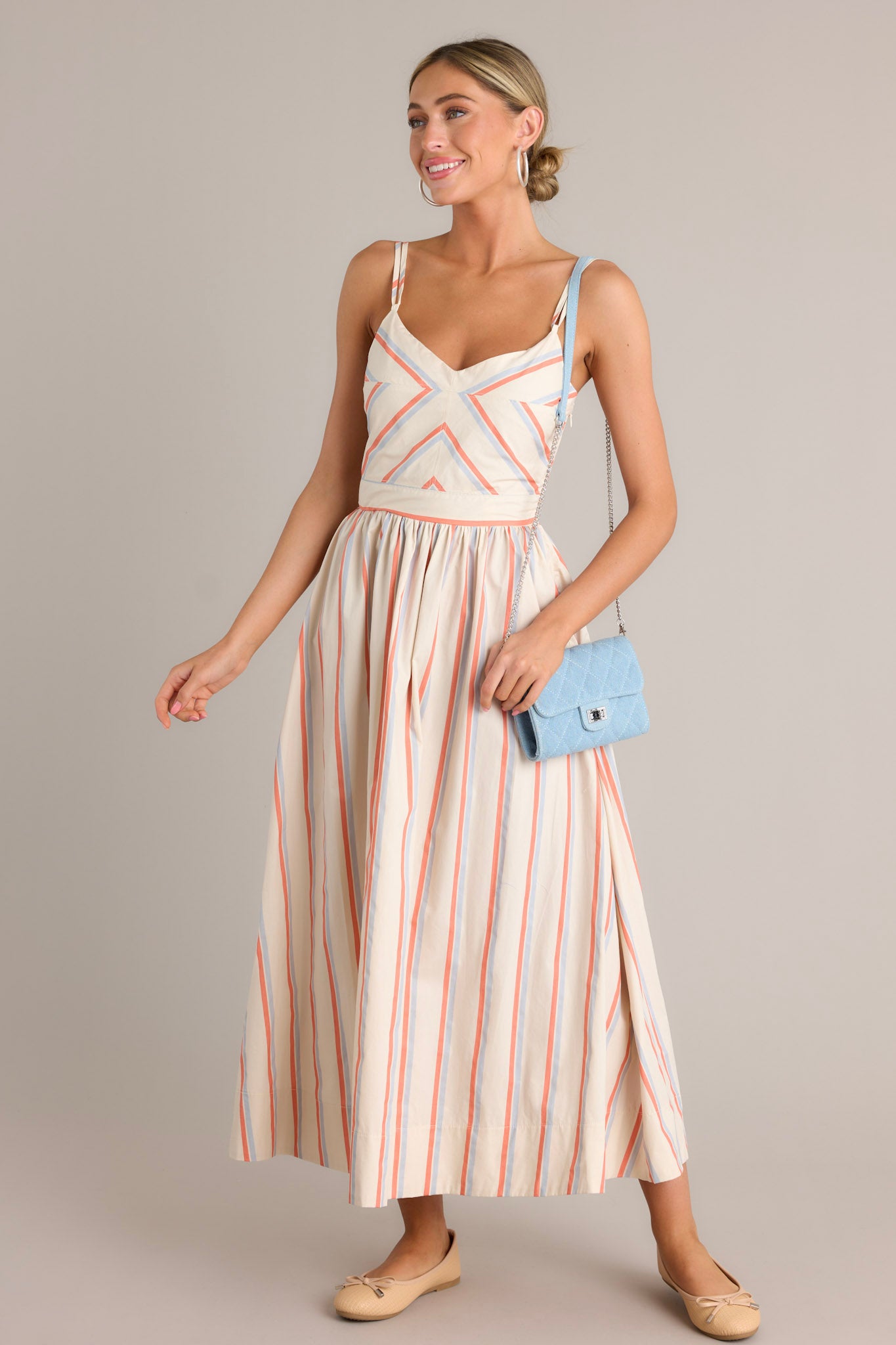 Full length view of a multi stripe dress with a v-neckline, thin adjustable double straps, a smocked back insert, a discrete side zipper, a flowing silhouette, and a thick hemline