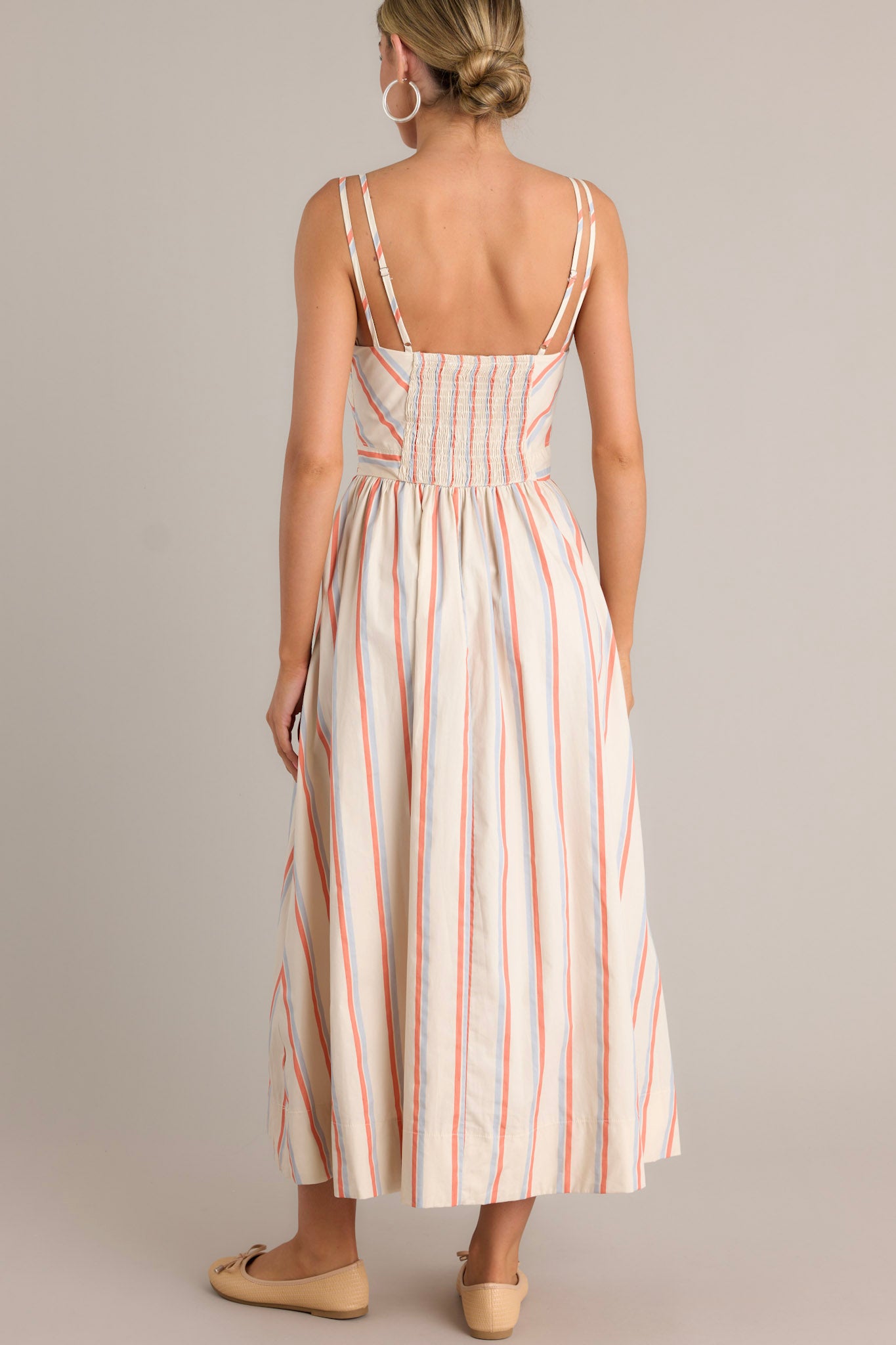 Back view of a multi stripe dress highlighting the smocked back insert, thin adjustable double straps, and overall fit.