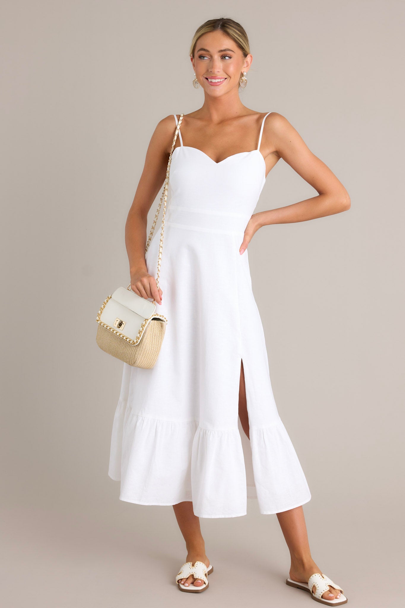 This white maxi dress features a sweetheart neckline, thin adjustable straps, a smocked back insert, a discrete zipper, a single tier, and a slit.
