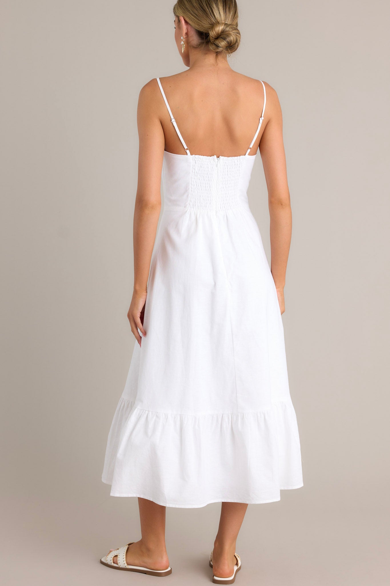 Back view of a white maxi dress highlighting the smocked back insert, thin adjustable straps, and overall fit.