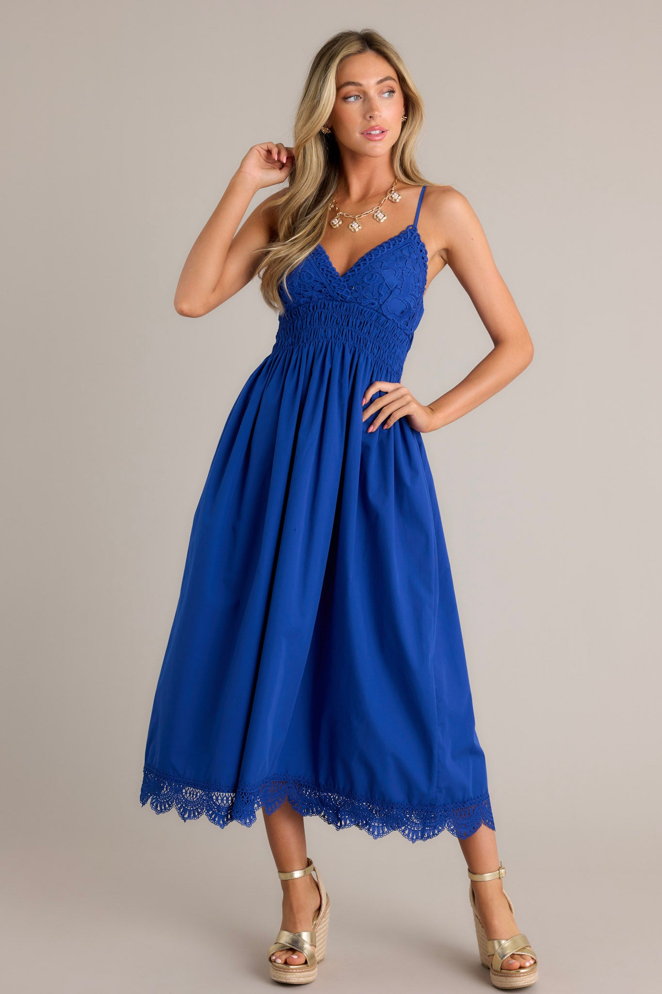 This blue maxi dress features a v-neckline, thin adjustable straps, a lace bust, a fully smocked waist & back, a flowing silhouette, and a lace hemline.