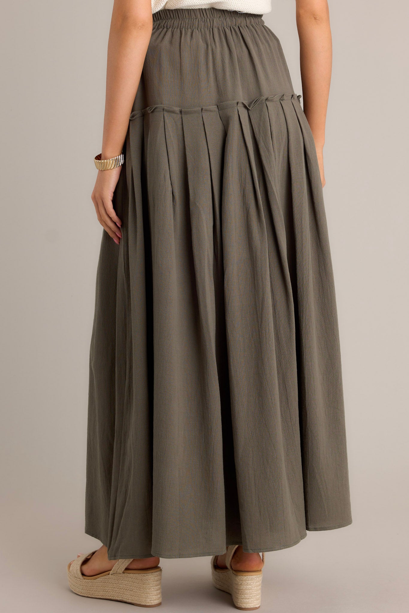 Back view of an olive maxi skirt highlighting the high waisted design, elastic waistband, and overall fit.