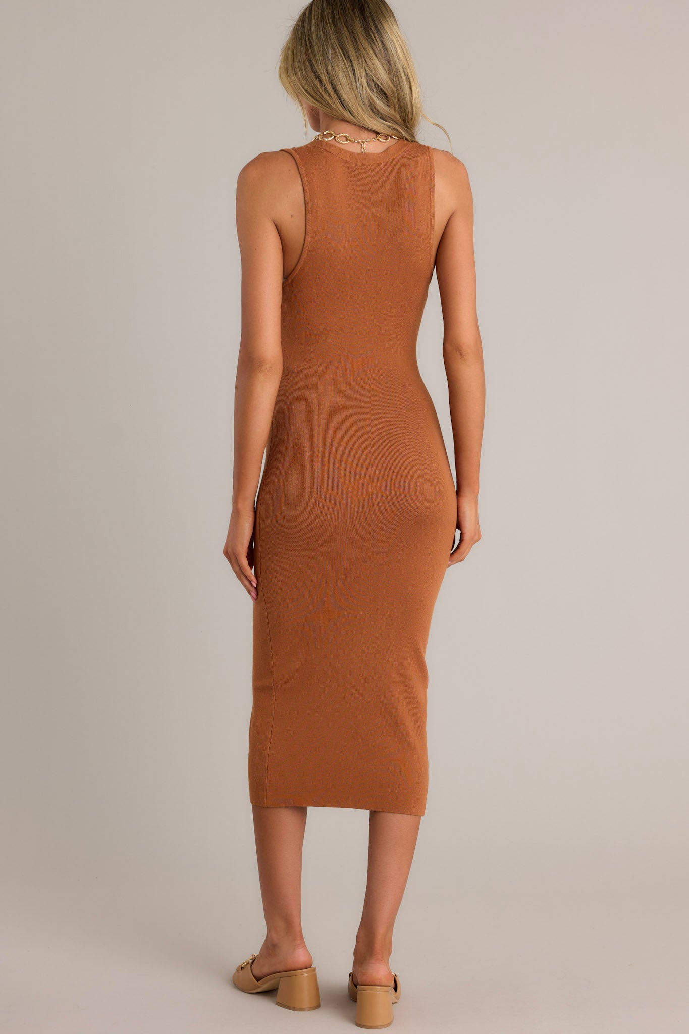 Back view of a brown midi dress highlighting the overall fit, ribbed texture, and figure-hugging silhouette.