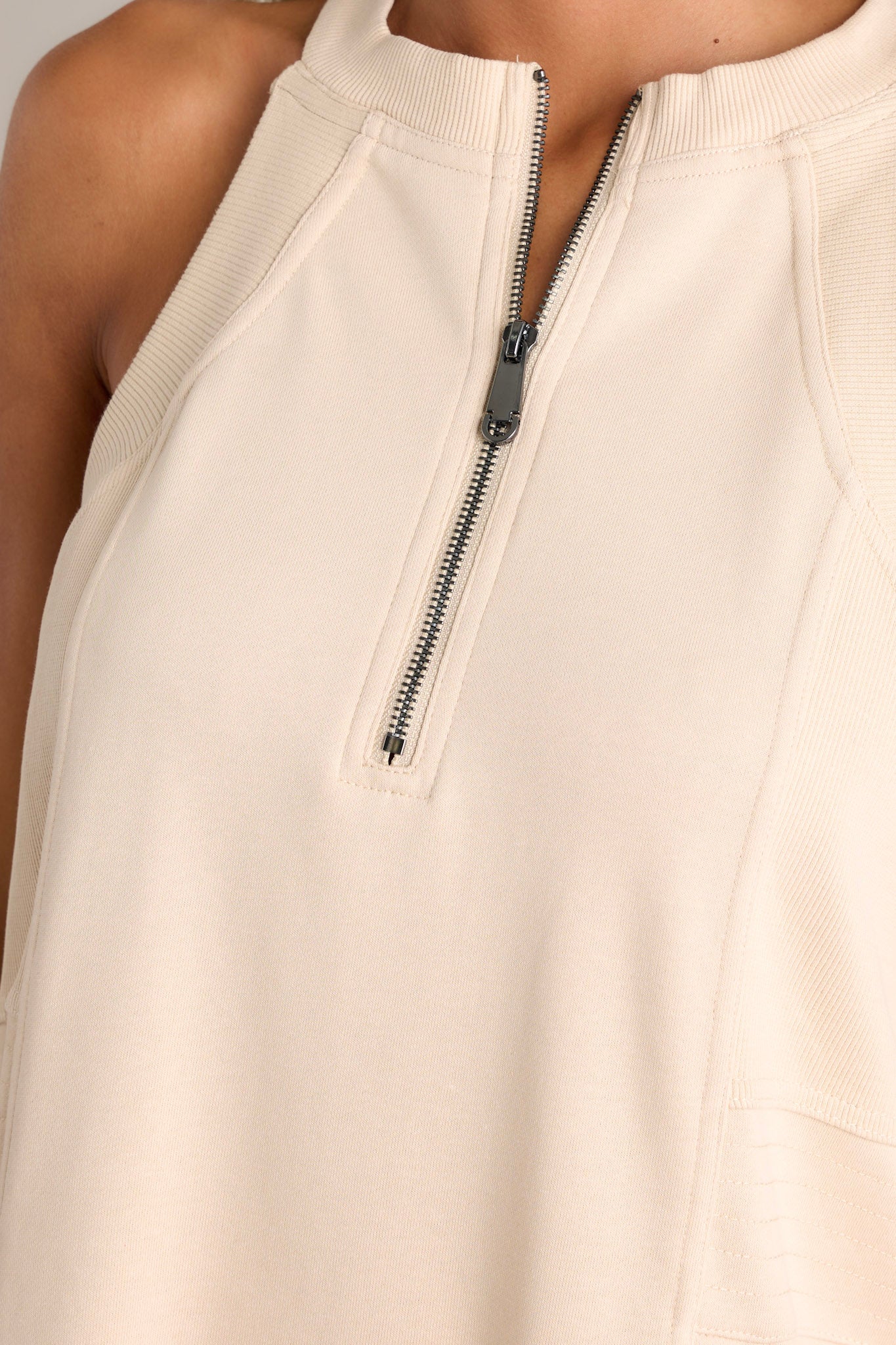Close-up of the beige mini dress showing the high neckline, functional zipper, and textured sides.