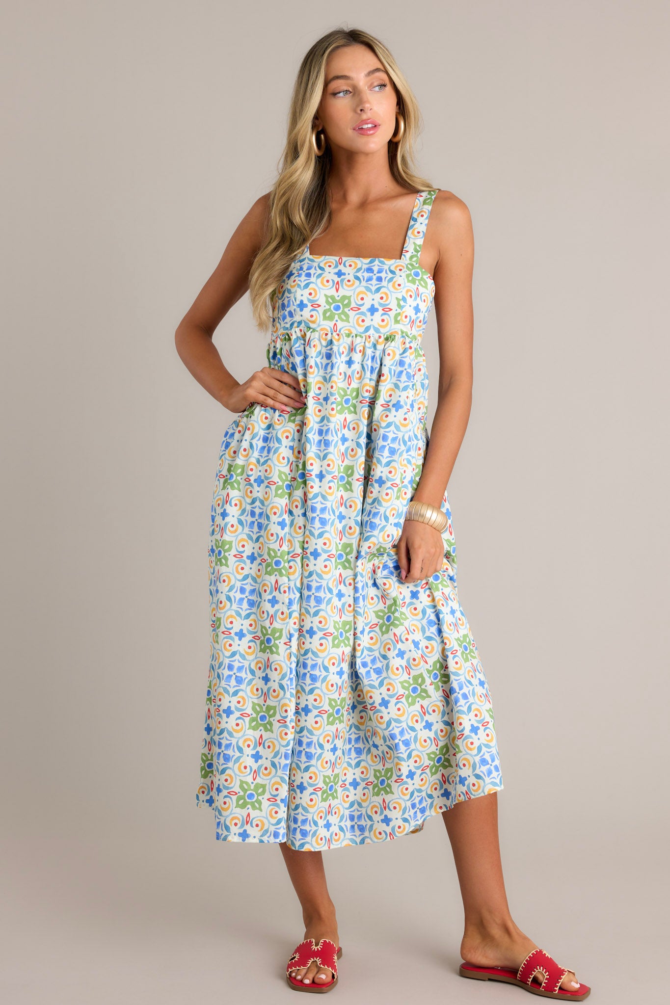 Front view of a white midi dress featuring a square neckline, self-tie adjustable straps, a colorful pattern, functional hip pockets, and a flowing silhouette.