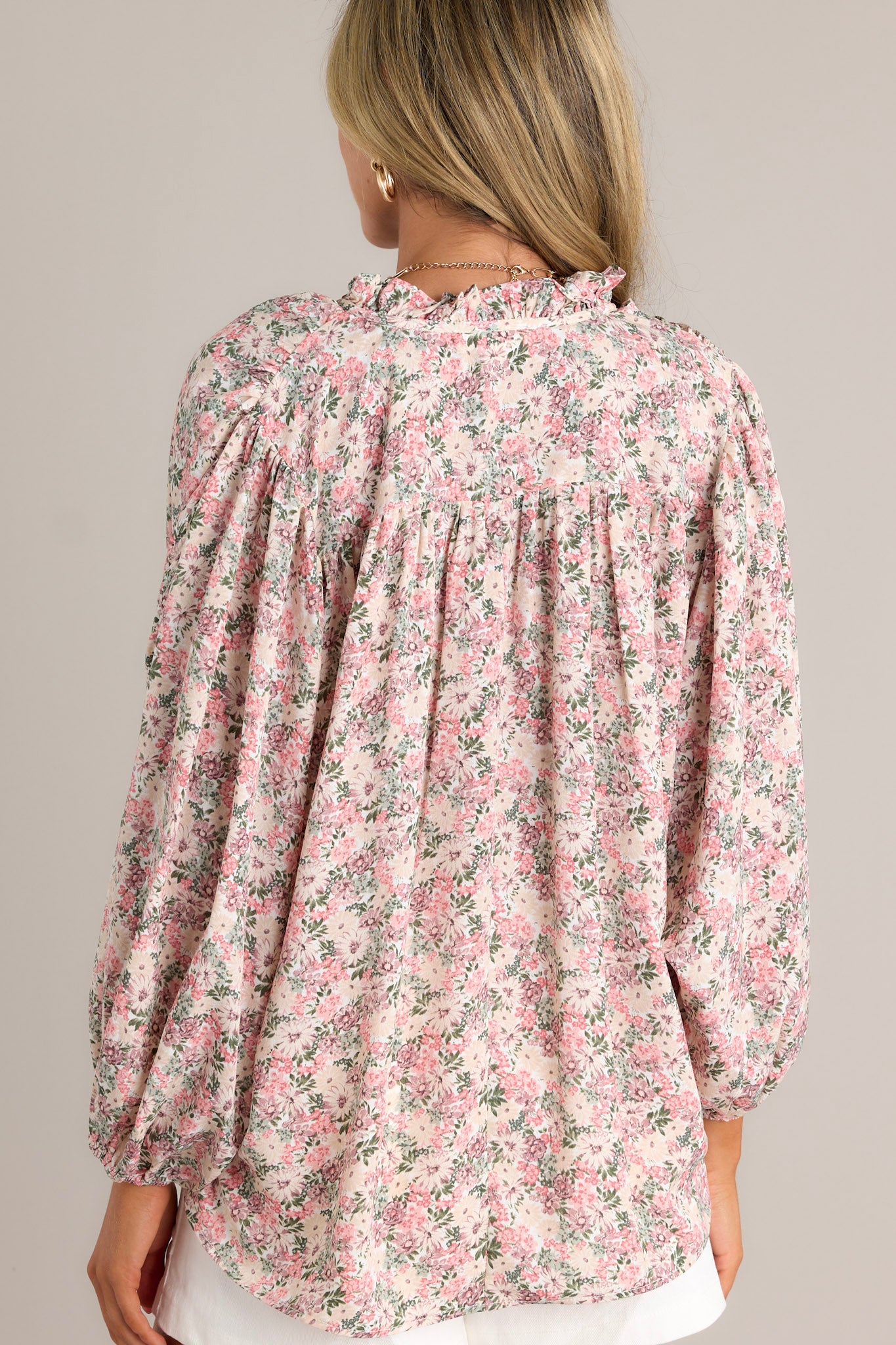 Back view of a pink floral top highlighting the gathering in the back, lightweight material, and overall fit.