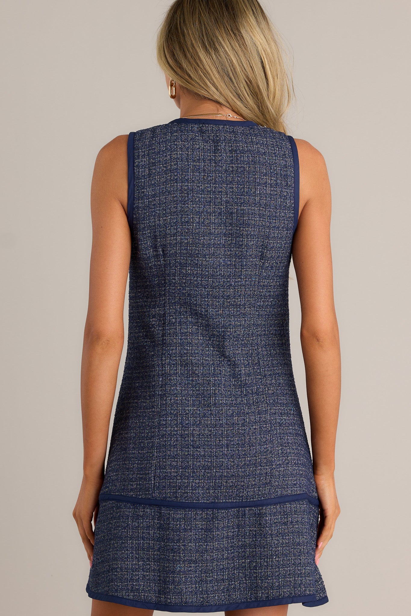 Back view of a navy mini dress highlighting the overall fit and sleeveless design.