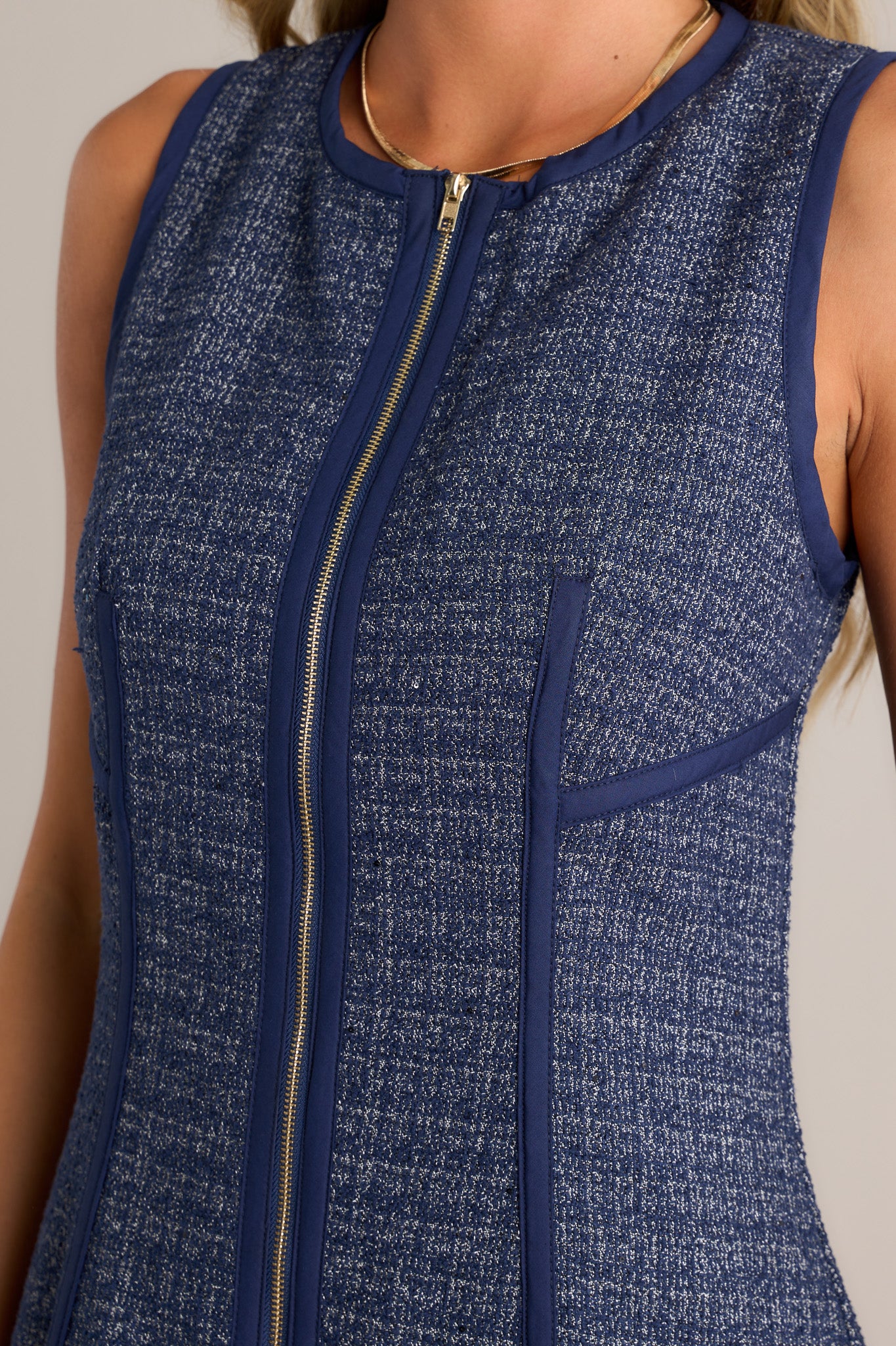 Close-up of the navy mini dress showing the high crew neckline, functional zipper front, thick front seams, and tweed material.