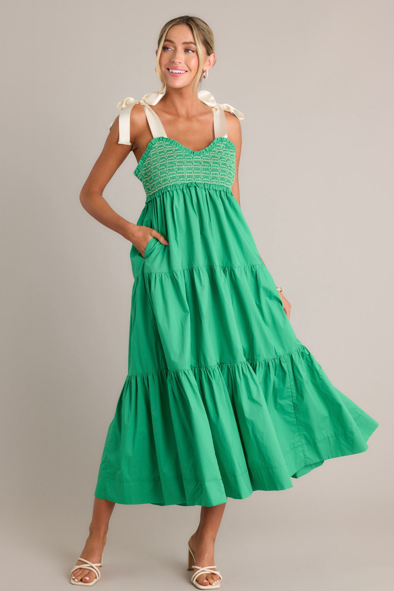 This green maxi dress features a v-neckline, thick self-tie straps, a fully smocked bodice, functional hip pockets, and a tiered design.