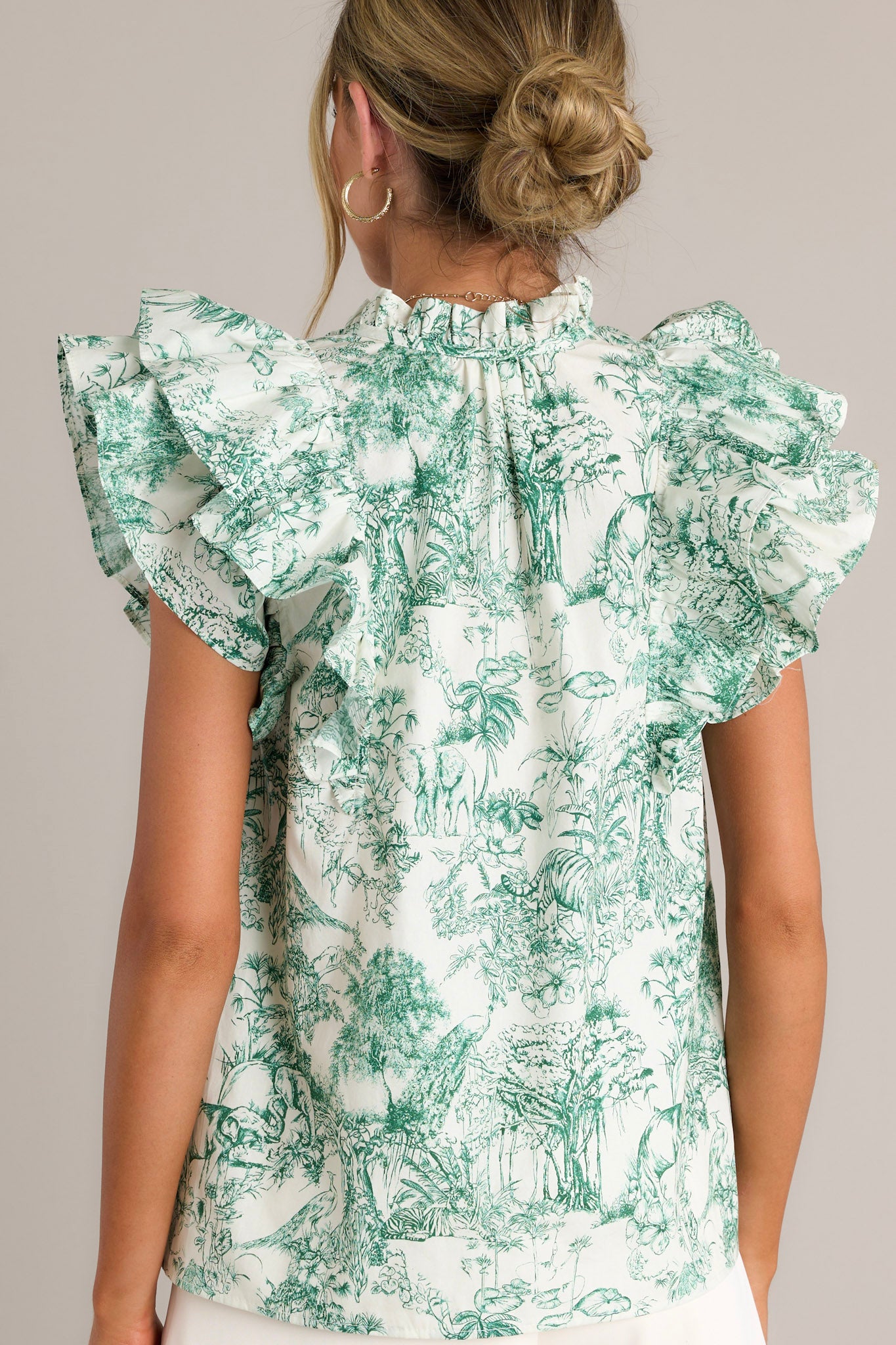 Back view of a green top highlighting the ruffle sleeves, toile print, and overall fit.