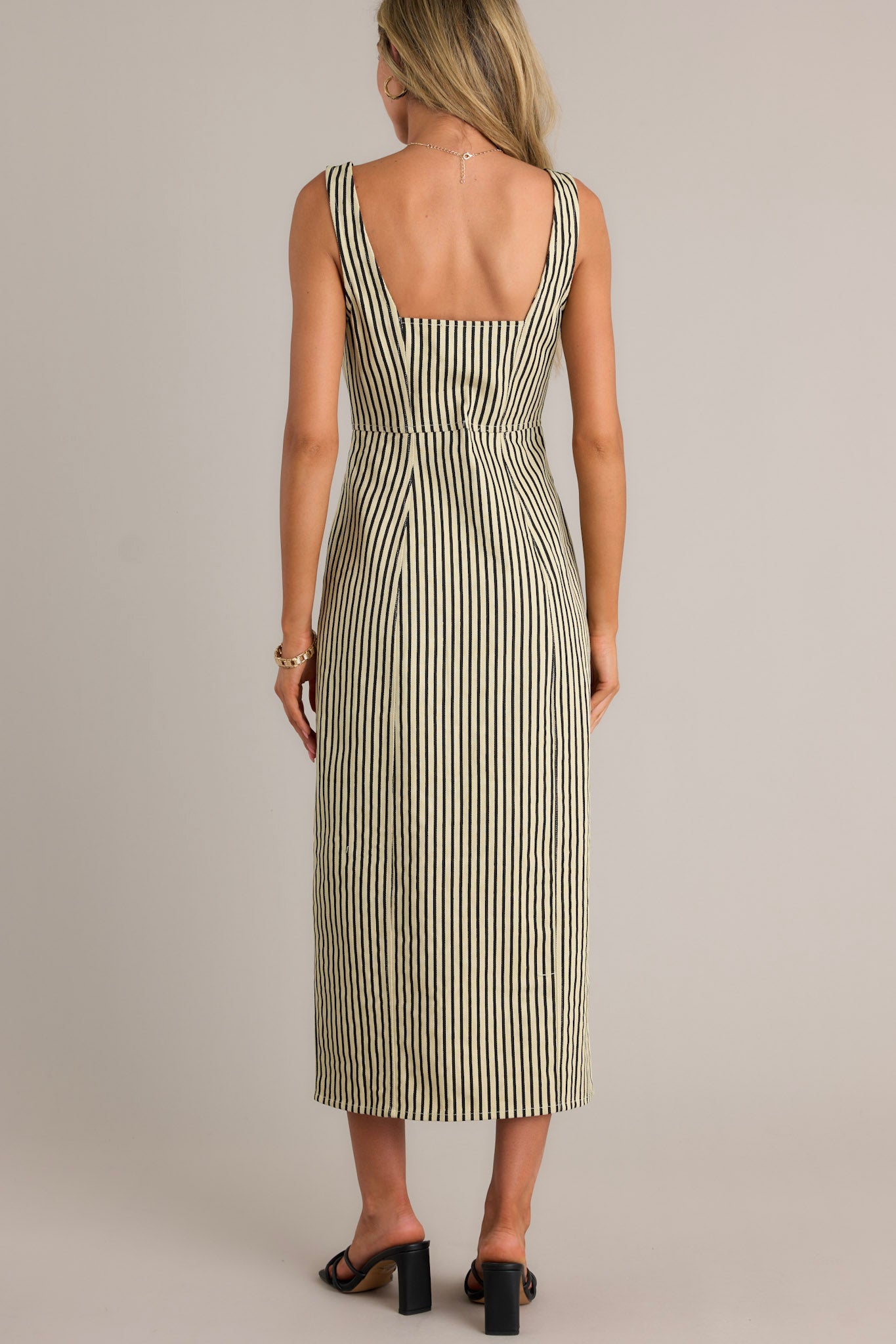 Back view of a black stripe maxi dress highlighting the thick straps, vertical stripe pattern, and overall fit.