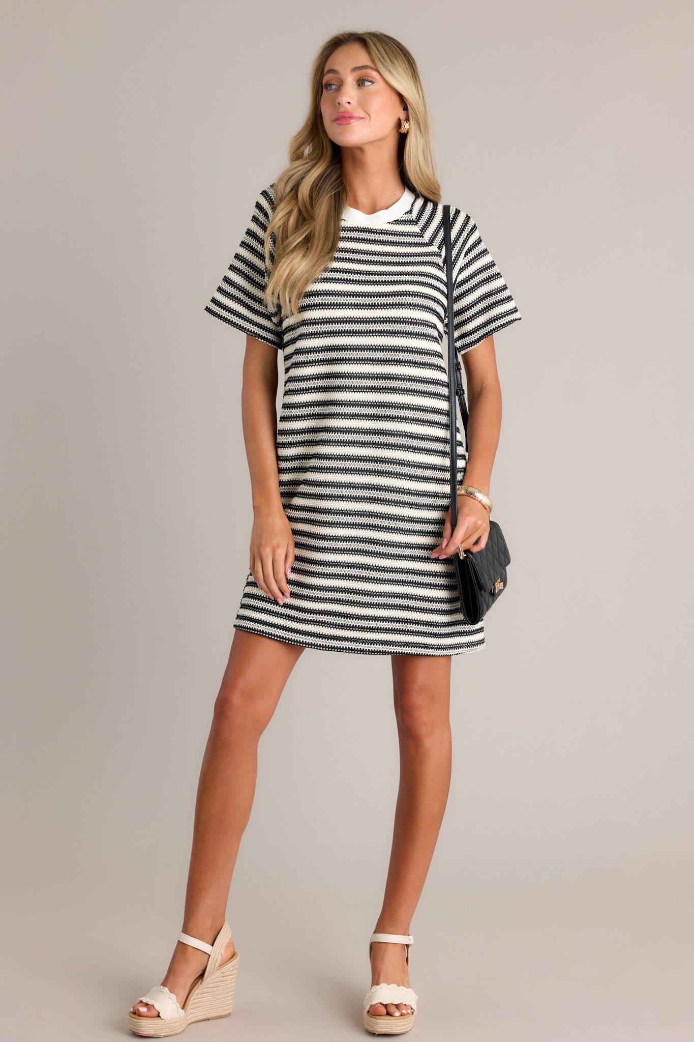 Full length view of a black stripe mini dress with a crew neckline, a knitted horizontal stripe design, a relaxed fit, and short sleeves