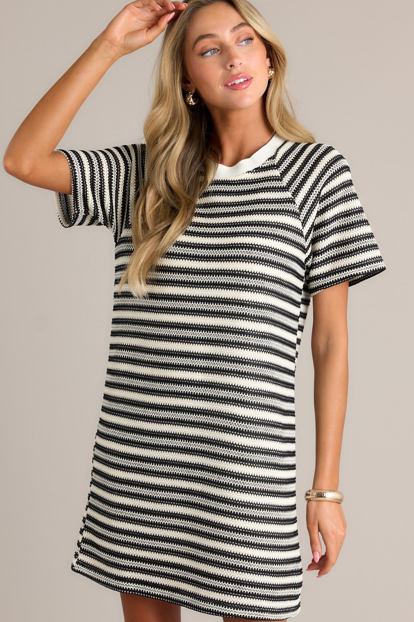 Front angled view of a black stripe mini dress featuring a crew neckline, a knitted horizontal stripe design, a relaxed fit, and short sleeves