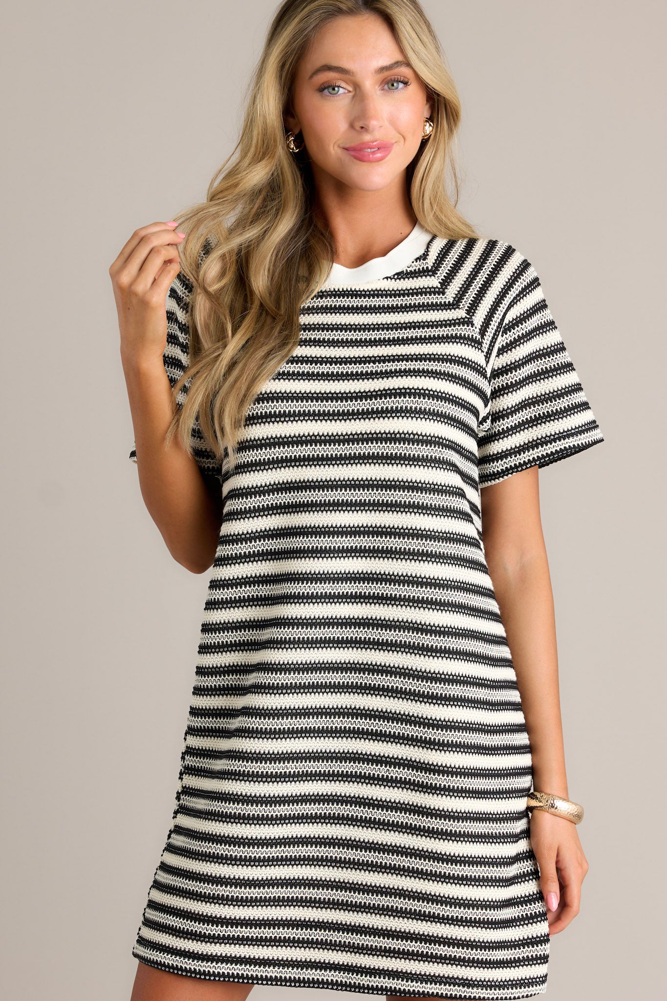 Front view of a black stripe mini dress featuring a crew neckline, a knitted horizontal stripe design, a relaxed fit, and short sleeves.