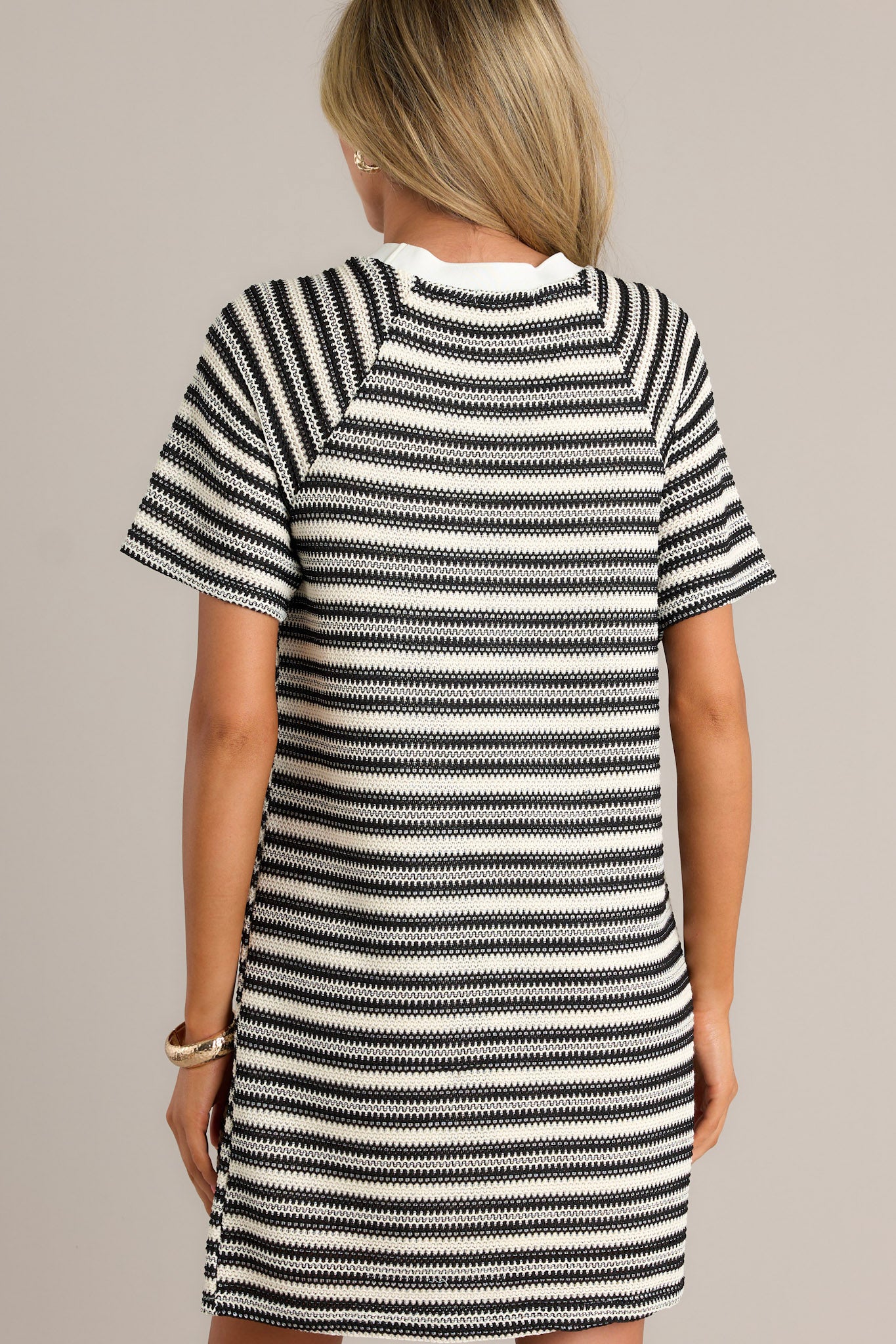 Back view of a black stripe mini dress highlighting the horizontal stripe design, relaxed fit, and overall fit.