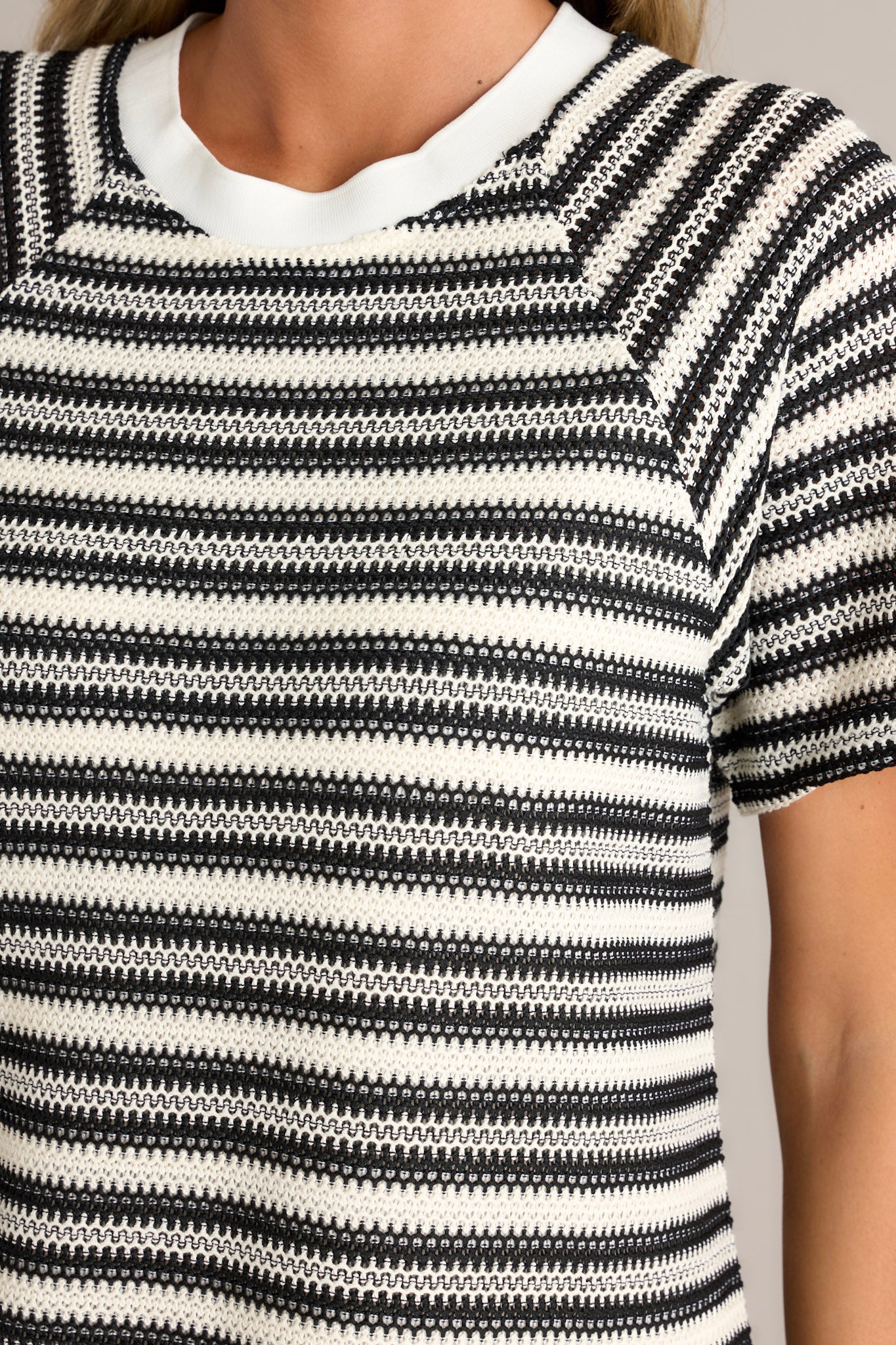 Close-up of the black stripe mini dress showing the crew neckline, knitted horizontal stripe design, and short sleeves.