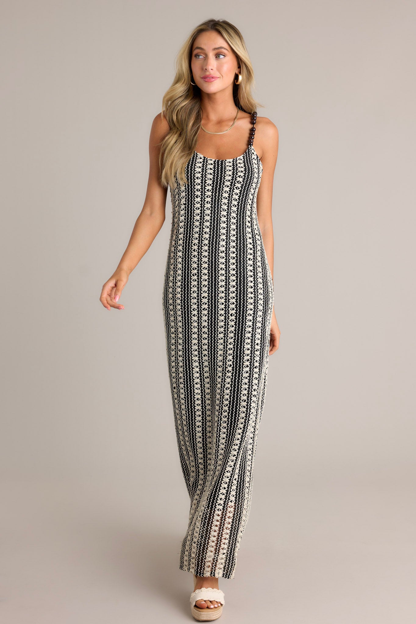 This black stripe maxi dress features a scoop neckline, fully beaded straps, a knitted design, and a vertical stripe pattern.