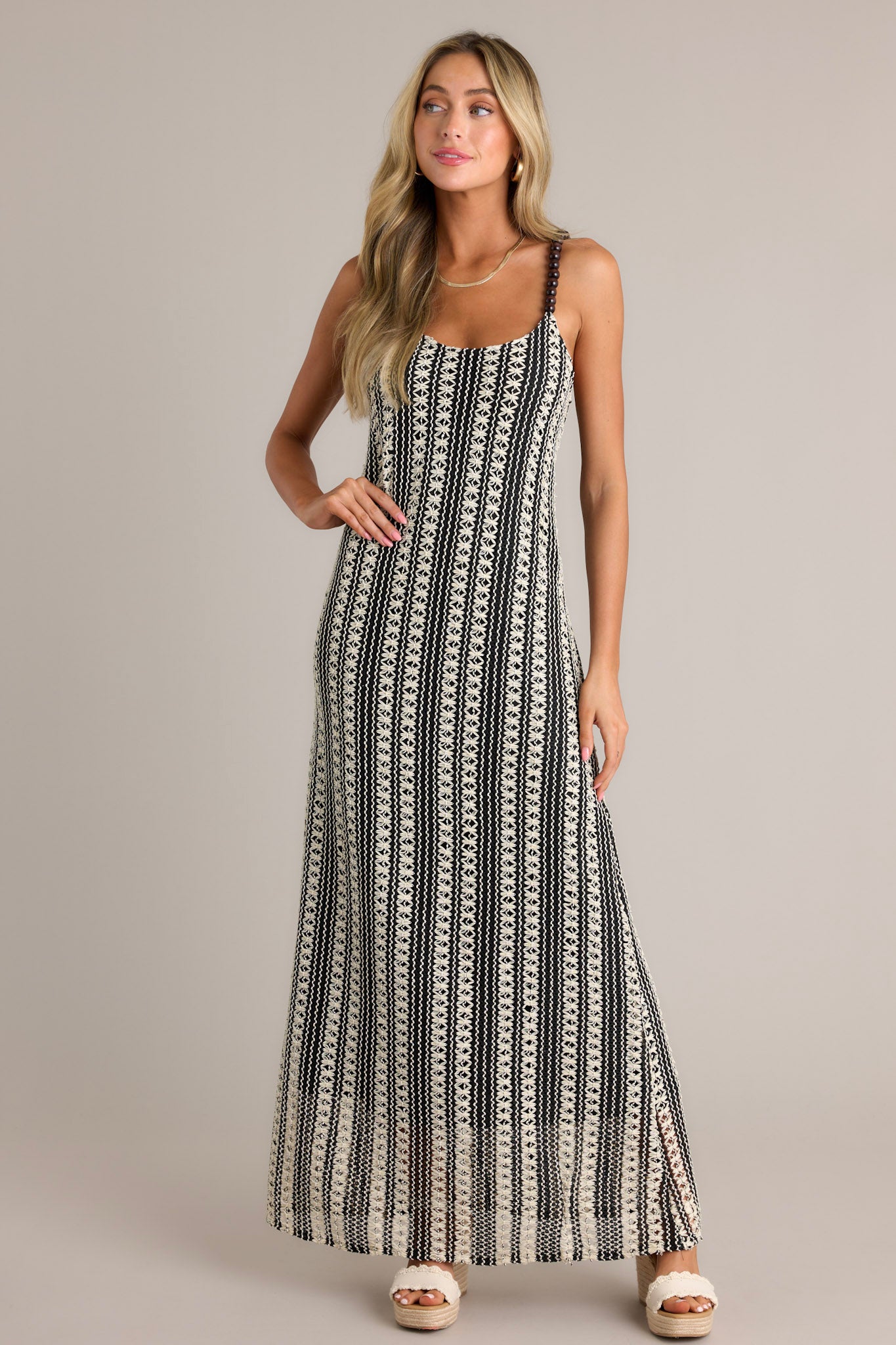 Front angled view of a black stripe maxi dress featuring a scoop neckline, fully beaded straps, a knitted design, and a vertical stripe pattern