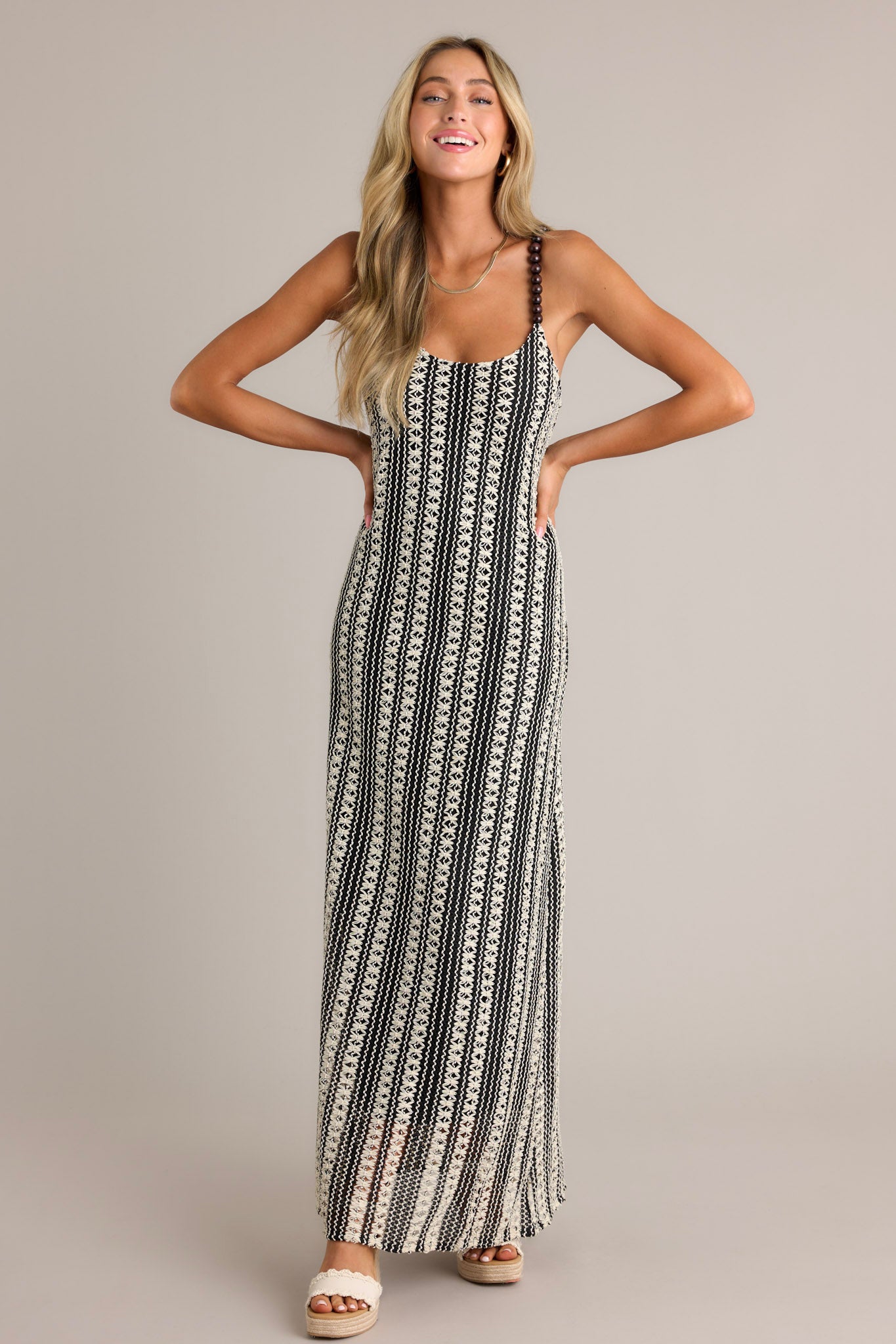 Front view of a black stripe maxi dress featuring a scoop neckline, fully beaded straps, a knitted design, and a vertical stripe pattern.