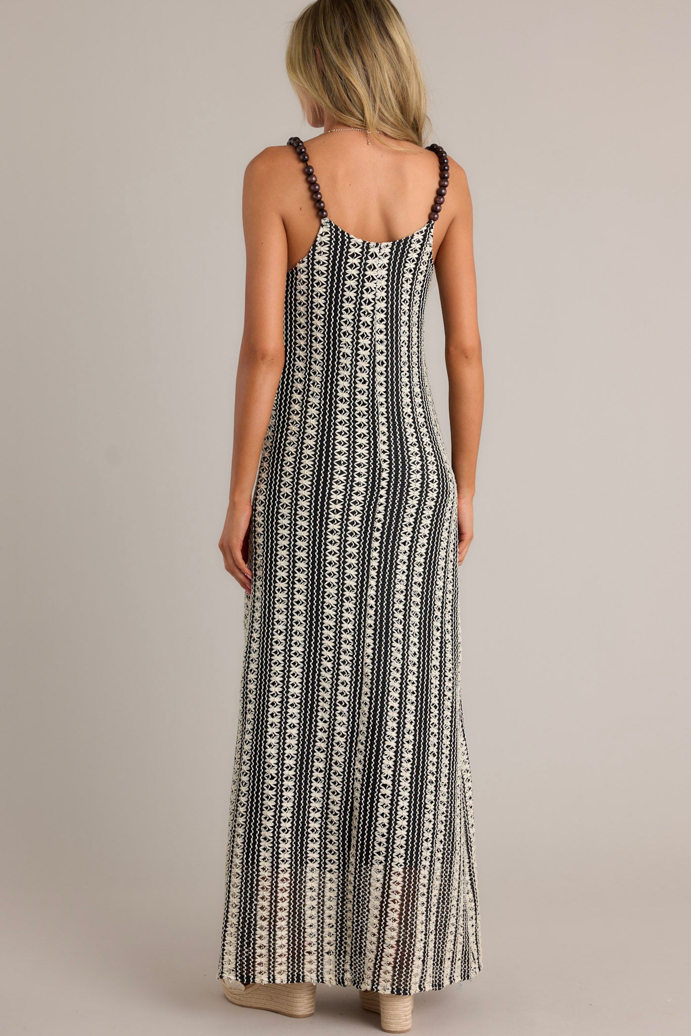 Back view of a black stripe maxi dress highlighting the fully beaded straps, knitted design, and overall fit.