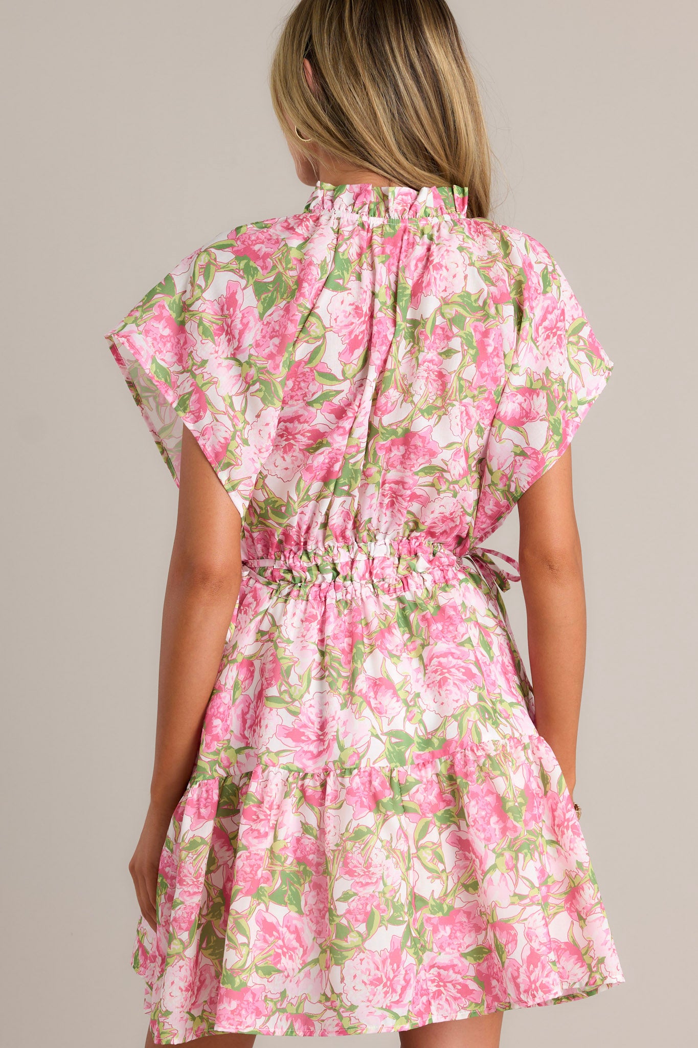 Back view of a pink dress highlighting the dolman sleeves, cinched waist, and overall fit.