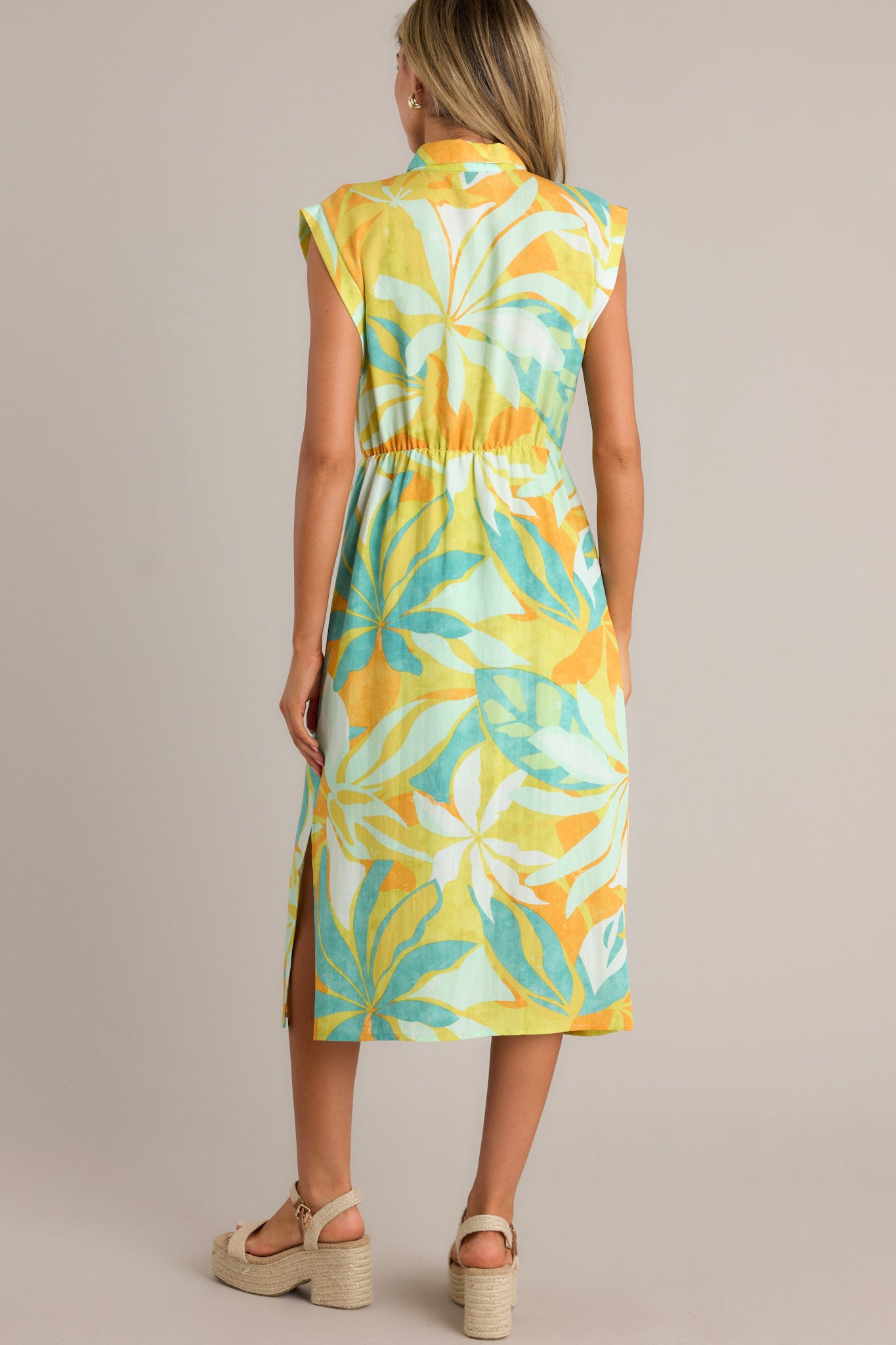 Back view of a lime green midi dress highlighting the elastic waistline, side slits, and overall fit.