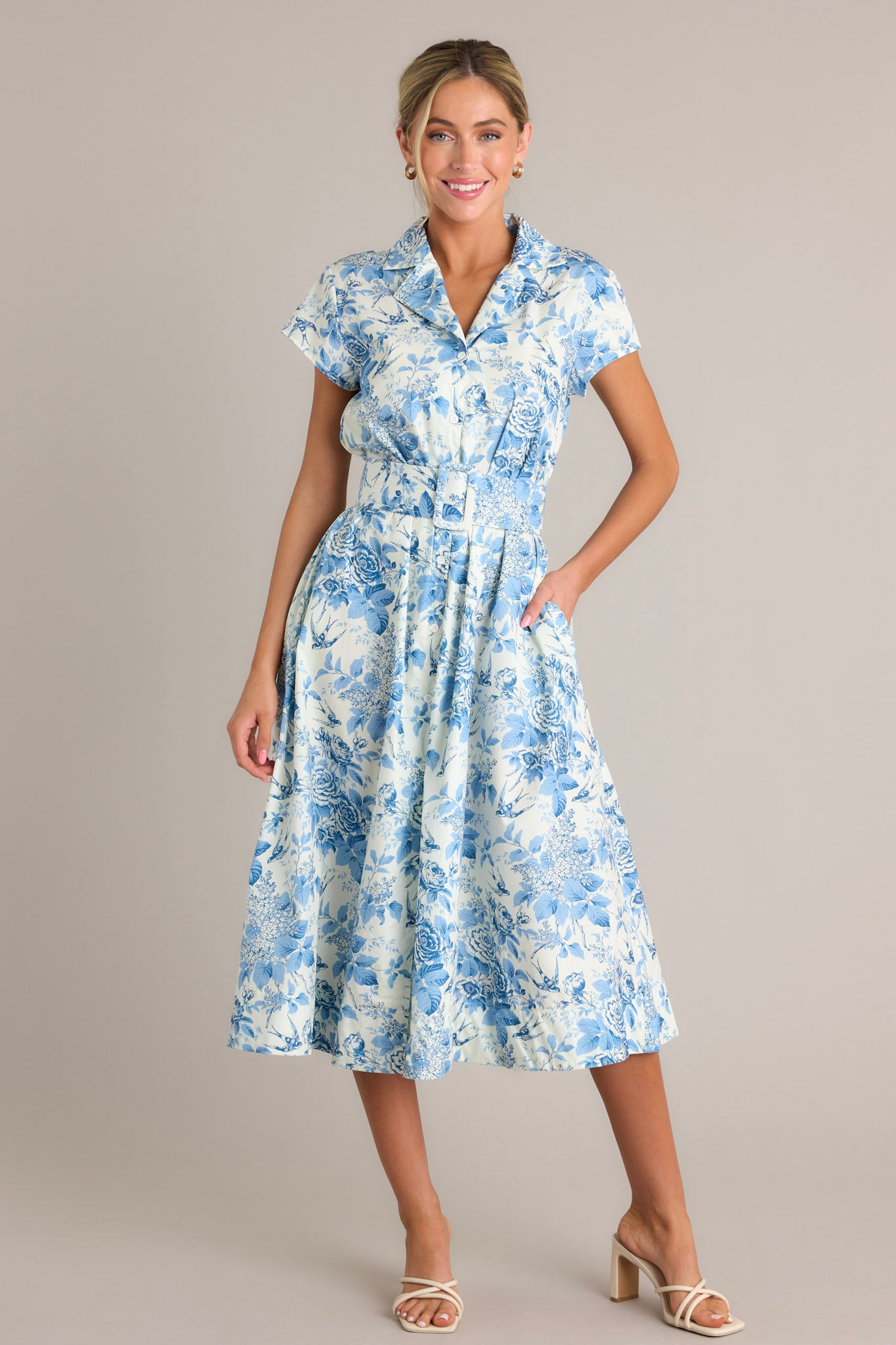 This dress features a notched lapel collared v-neckline, a full button front, belt loops, a functional belt, functional hip pockets, and a front slit.