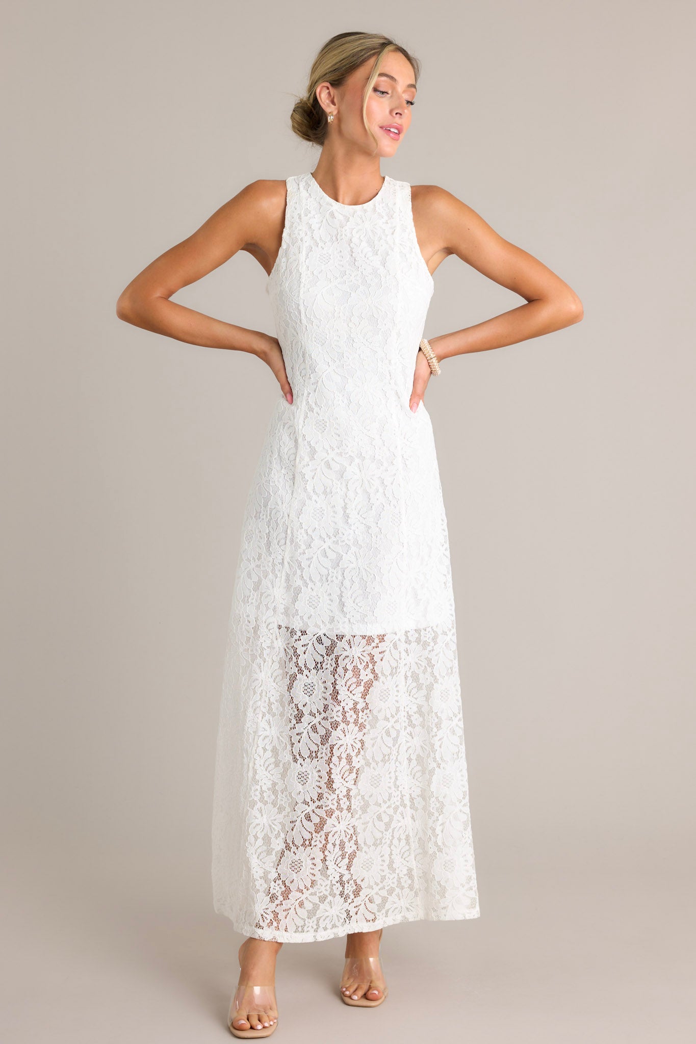 This dress features a high round neckline, a slip up the side, and a lace overlay with a lining that extends from the shoulder to the mid-thigh