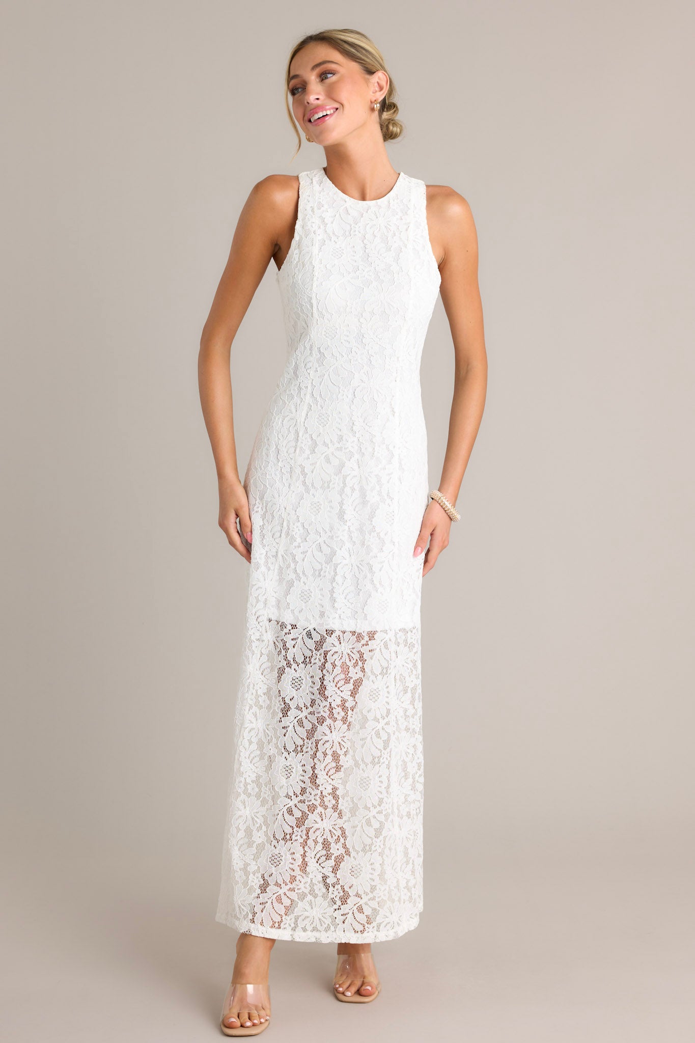 Full length view of a dress with a high round neckline, a slit up the side, and a lace overlay with a lining that extends from the shoulder to the mid-thigh