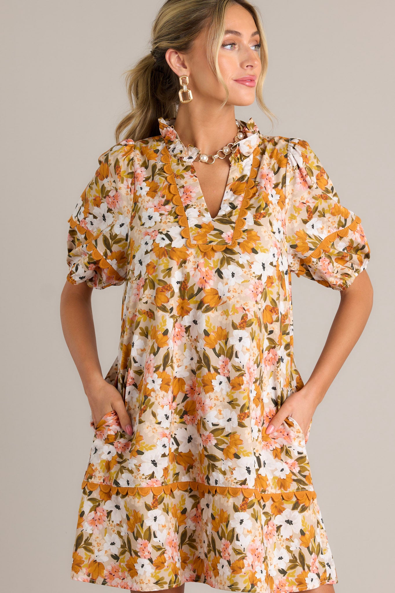 Front angled view of a yellow mini dress featuring a ruffled v-neckline, scalloped detailing, a relaxed fit, and elastic cuffed short sleeves