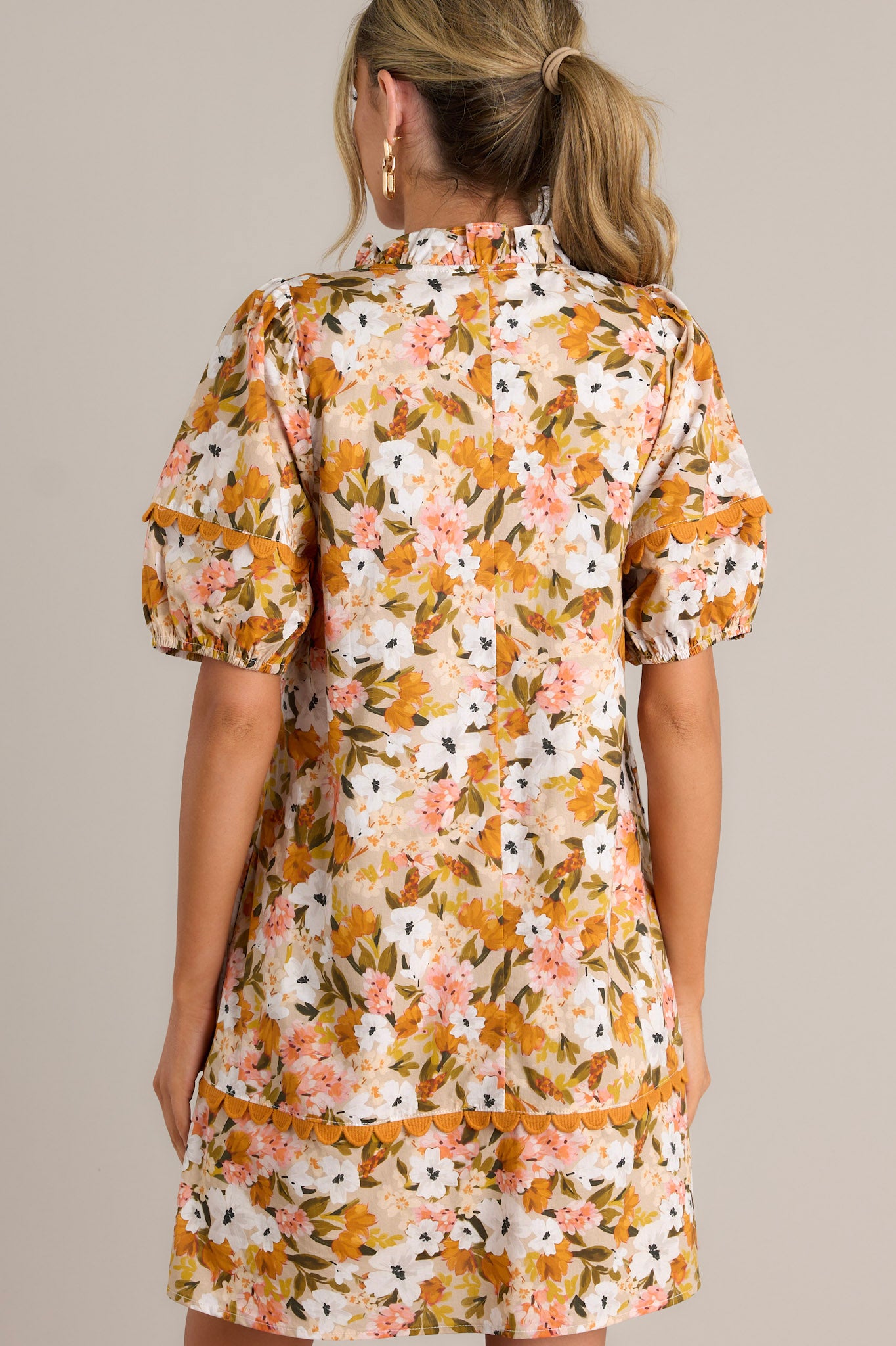 Back view of a yellow mini dress highlighting the relaxed fit, scalloped detailing, and overall fit.