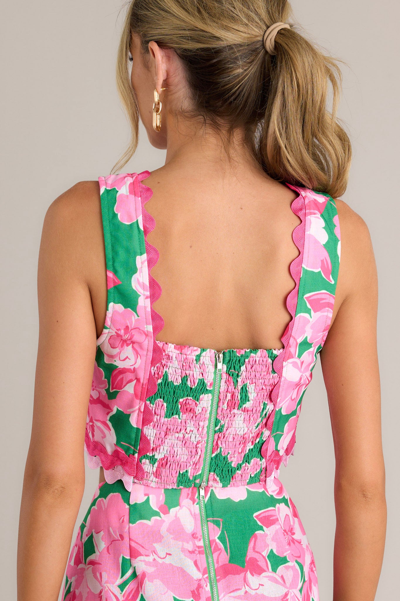 Back view of a green floral crop top highlighting the smocked back insert, zipper, and overall fit.