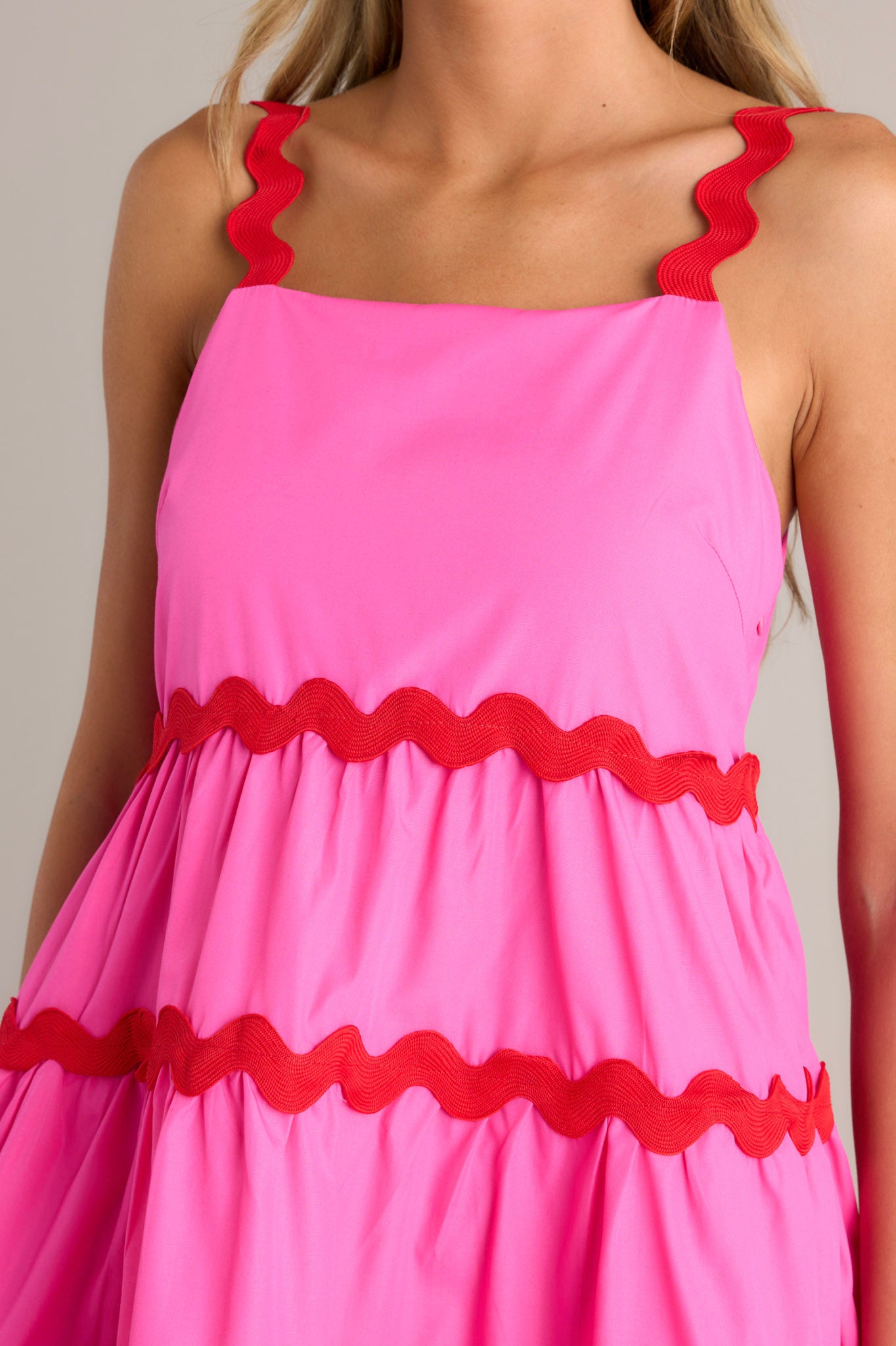 Close-up of the hot pink mini dress showing the square neckline, ricrac straps, and ricrac tiers.