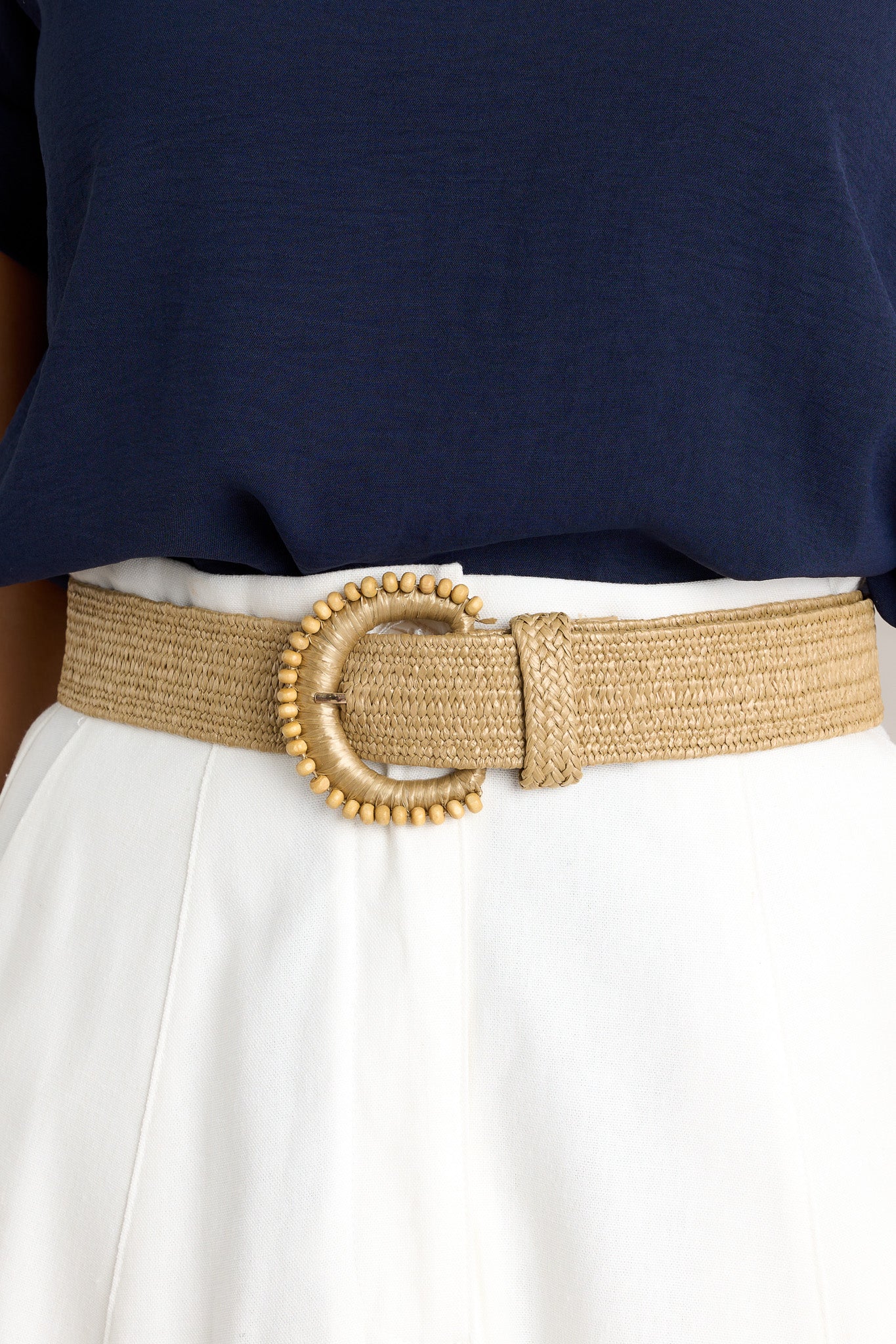 Close-up view of this khaki belt that features a gold hardware, an elastic band, and a rounded buckle with beaded detailing.&nbsp;