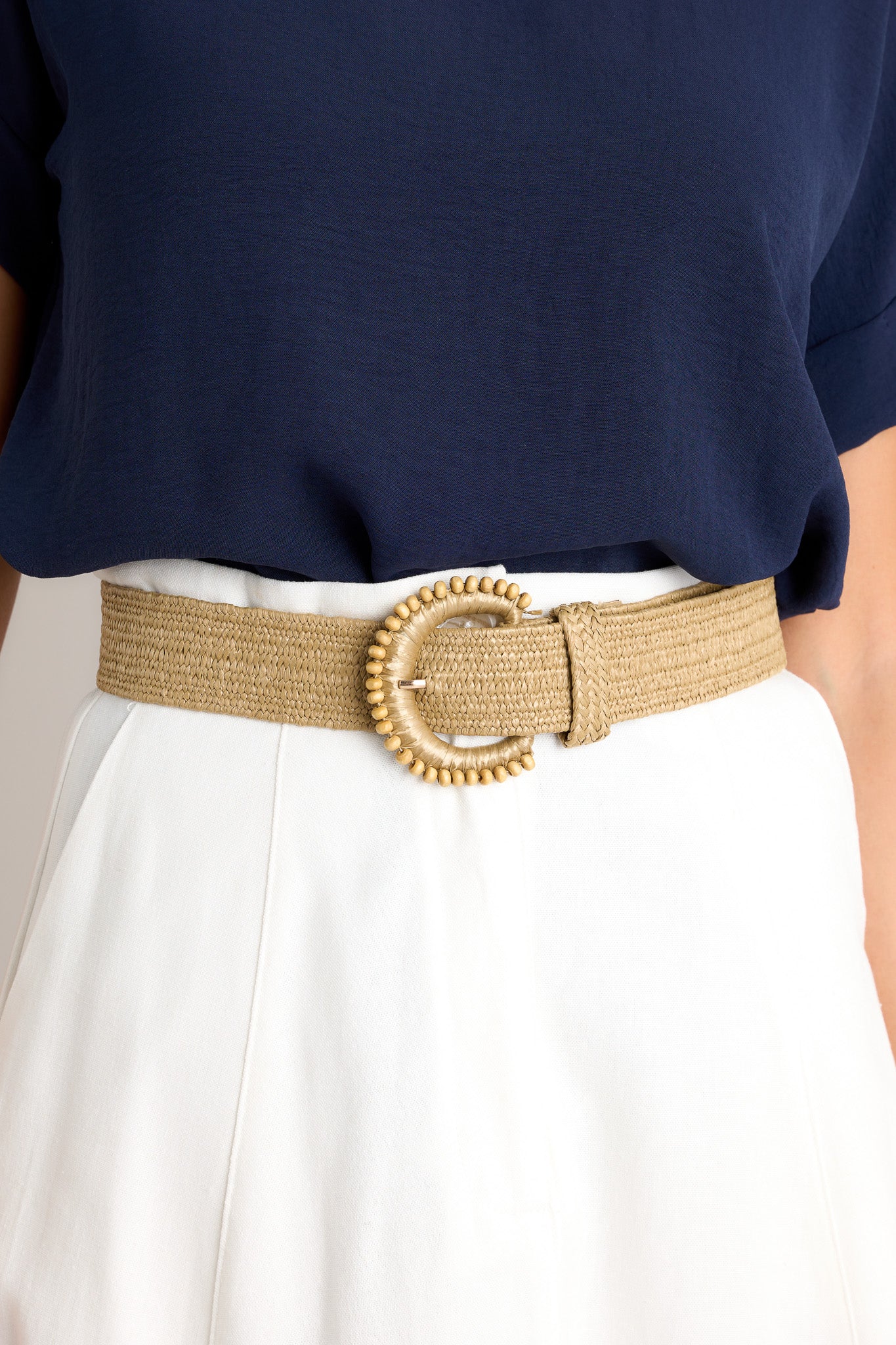 This khaki belt features a gold hardware, an elastic band, and a rounded buckle with beaded detailing.