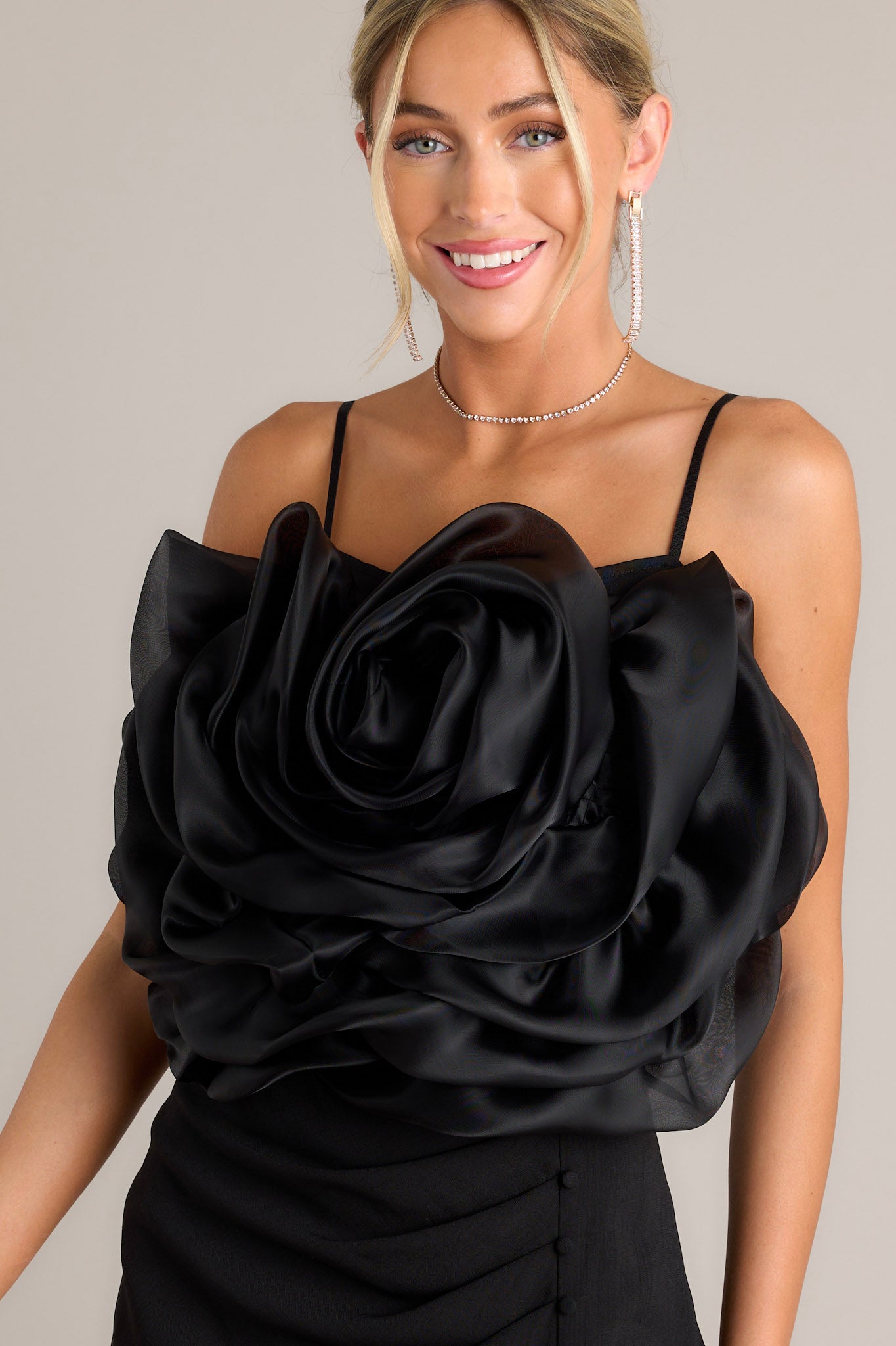 This black crop top features a square neckline, thin & stretchy adjustable straps, a fully smocked back, a large 3-D flower, and a cropped hemline.